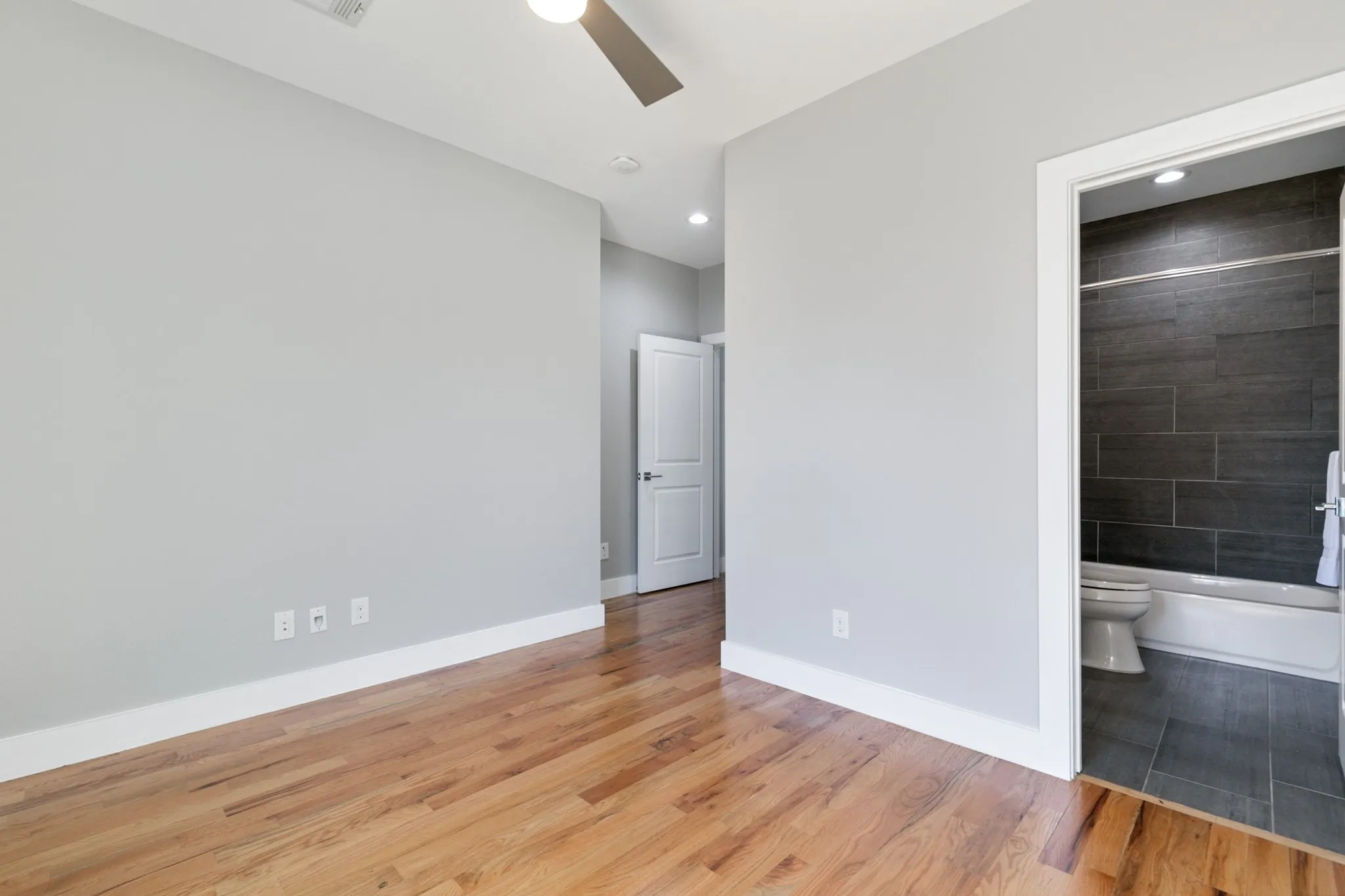 Hardwood flooring, light gray wall finishes, white trim, recessed lighting, and a ceiling fan