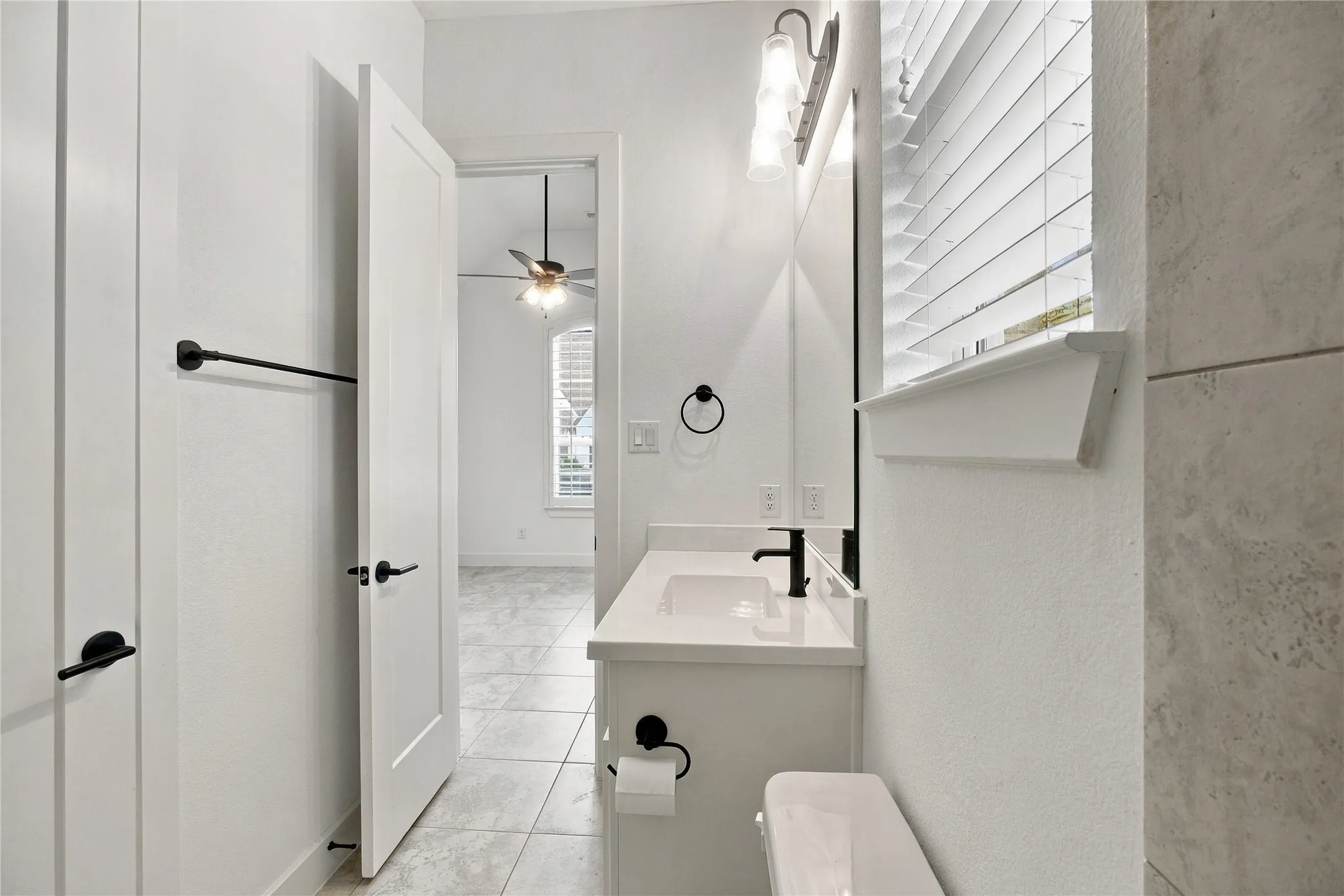 Full bathroom ensuite third bedroom featuring a single vanity with a white countertop, matte black faucet