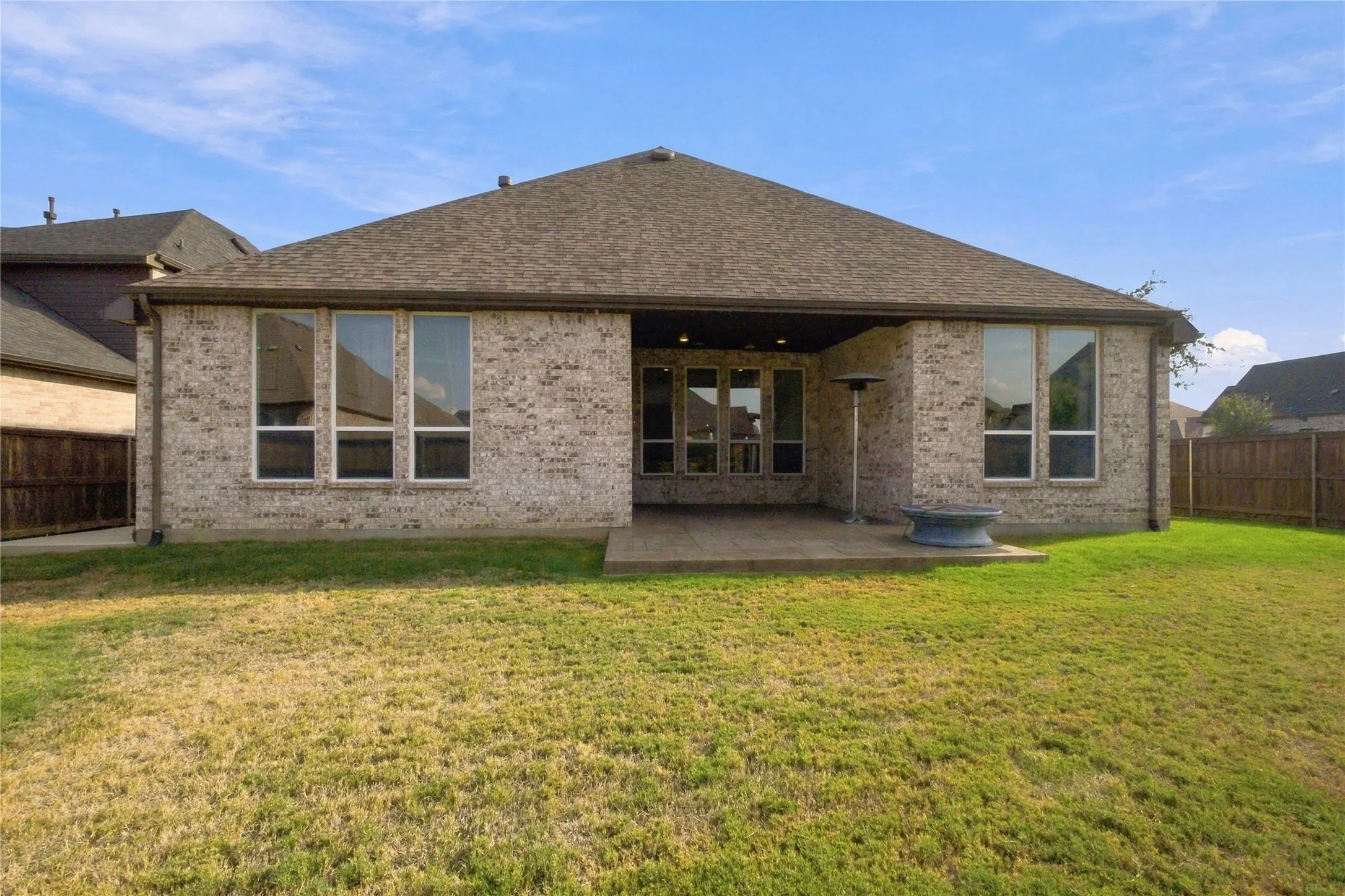 Brick exterior with a covered patio and multiple large windows