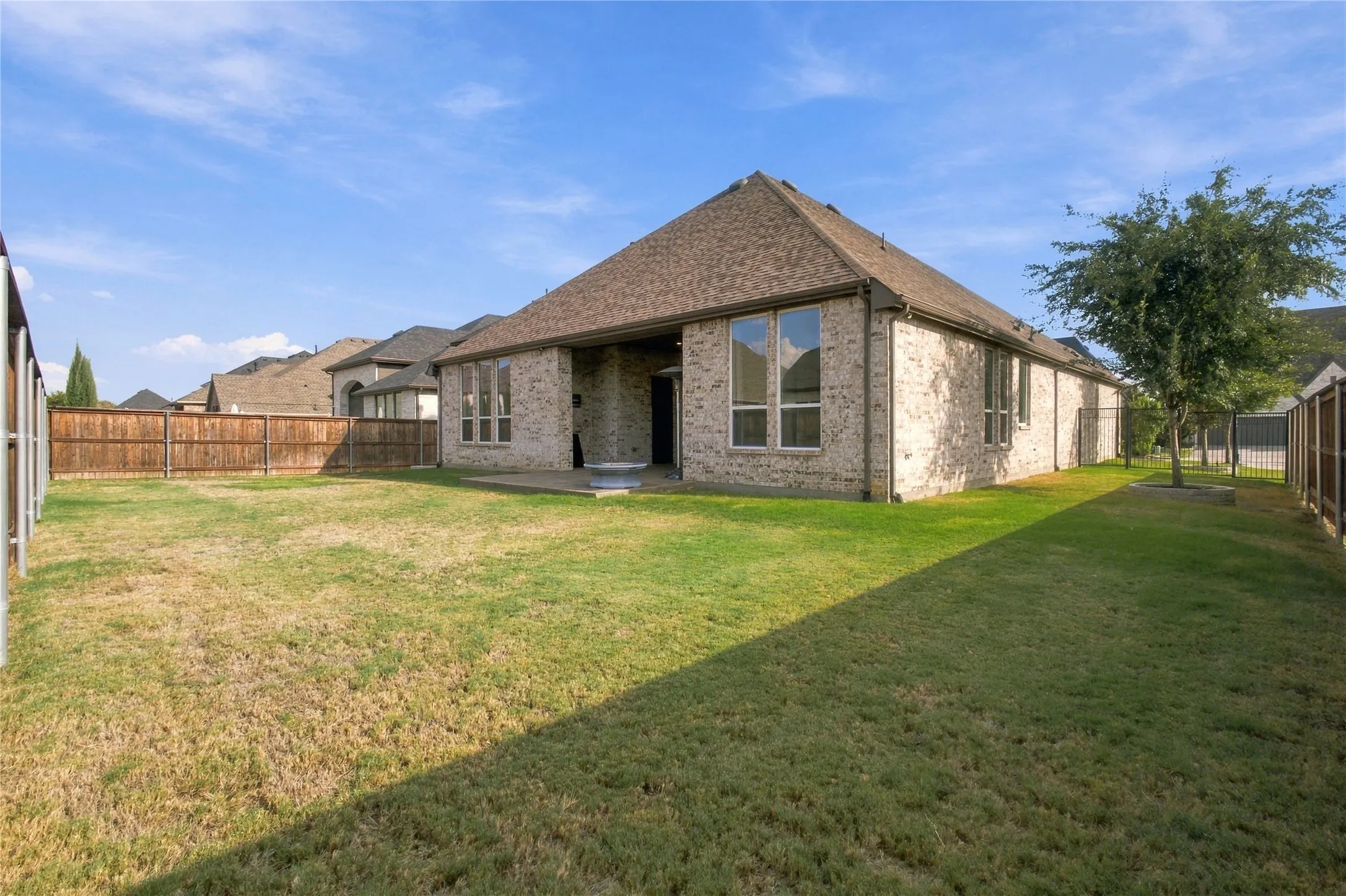 Expansive backyard with a manicured lawn, full privacy fencing, and a concrete patio
