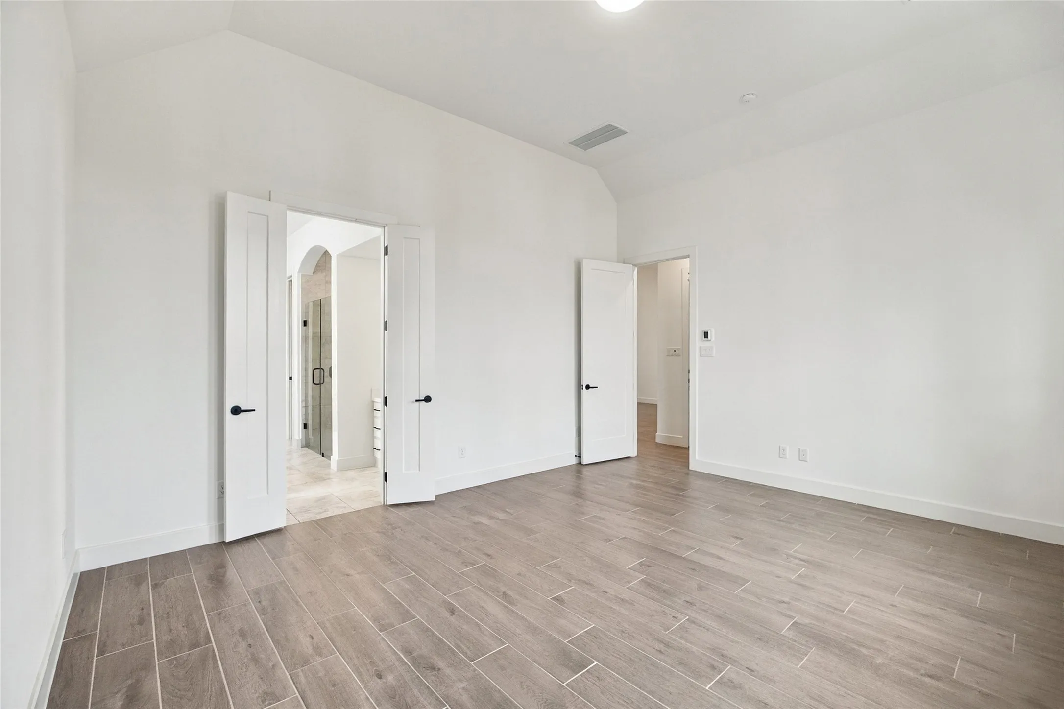 1st primary bedroom 14x17 featuring vaulted ceiling, wood-finish flooring