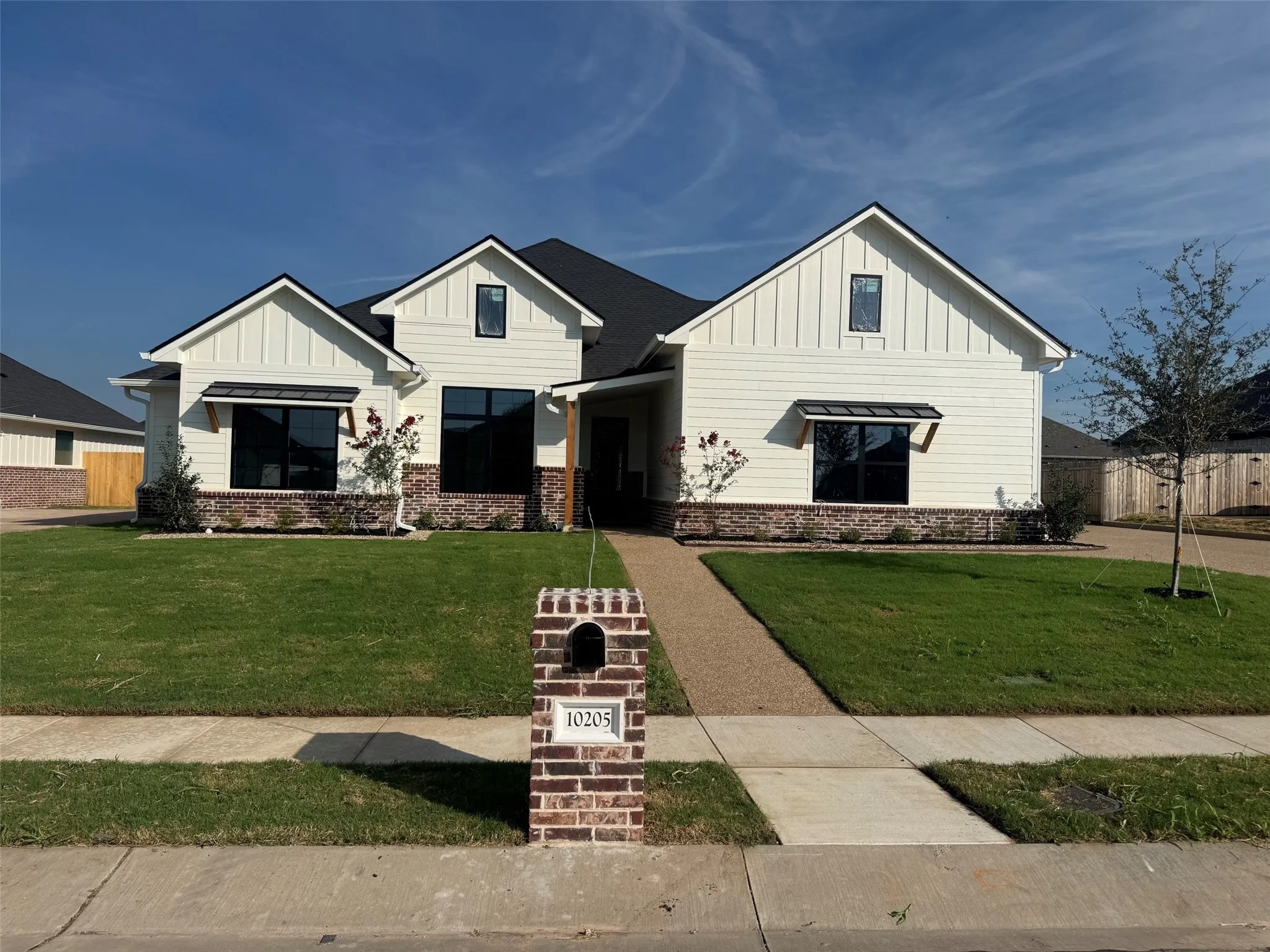 White board-and-batten and horizontal siding exterior with brick accents