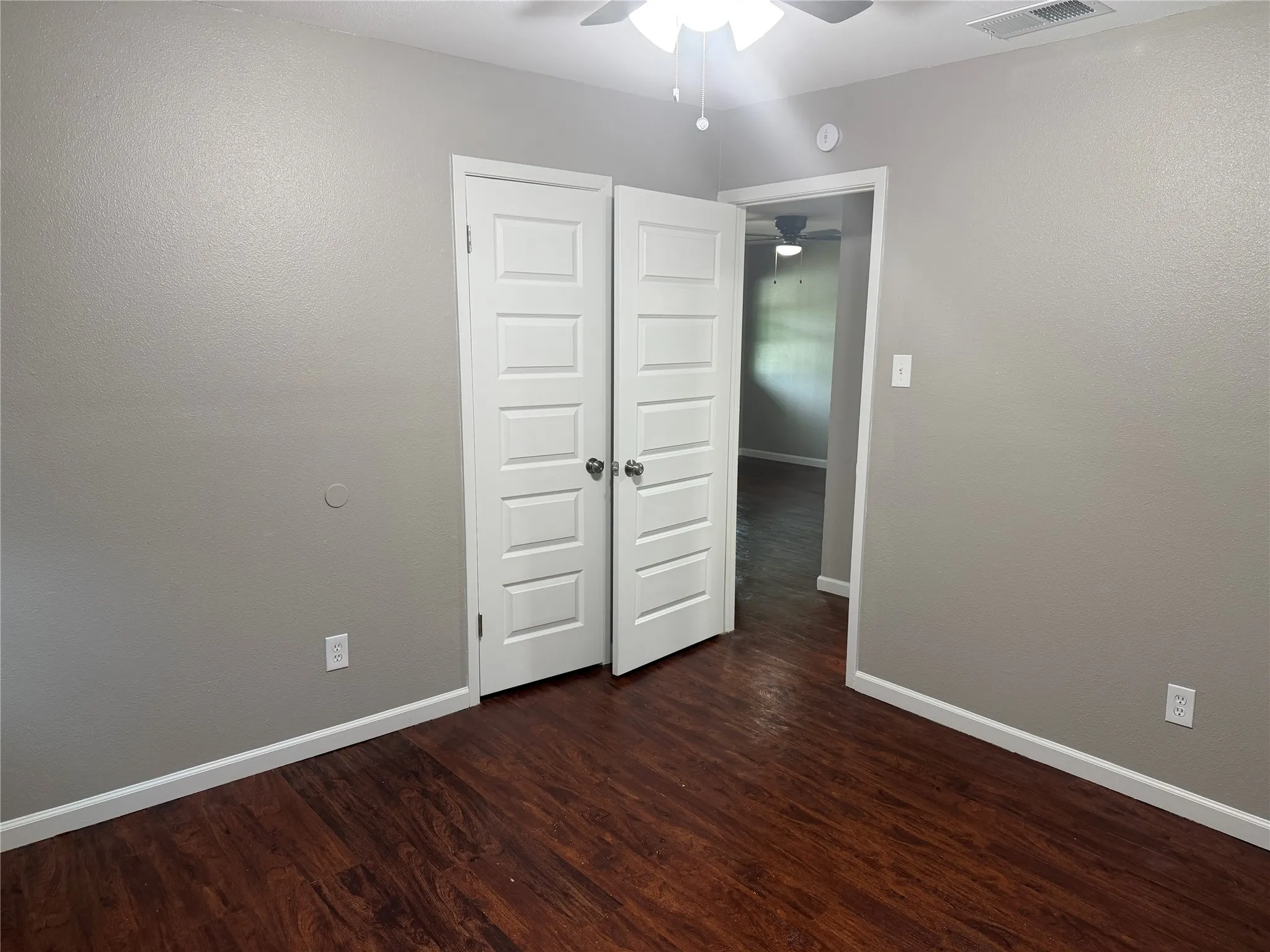 Wood-finish flooring, light gray walls, white trim, and white paneled doors