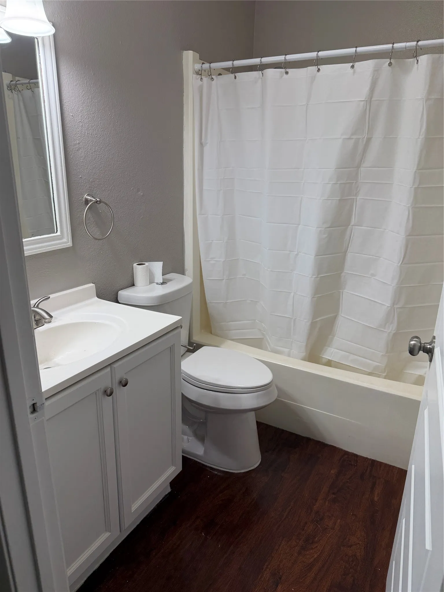 Dark wood-finish flooring with a white vanity featuring a basin sink and chrome faucet