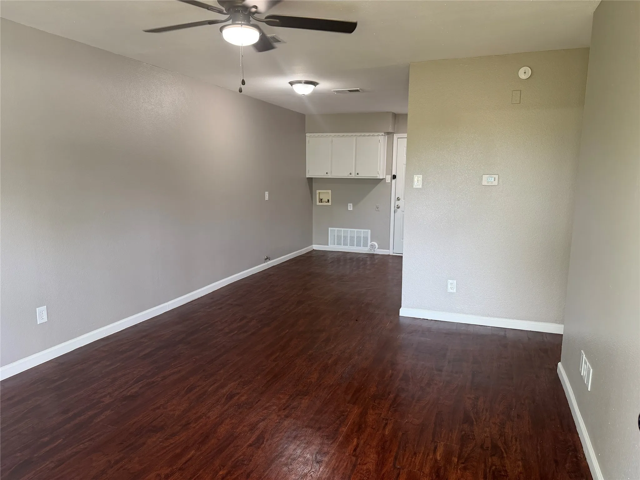 Wood-finish flooring, neutral wall tones, ceiling fan, recessed lighting, and white cabinetry