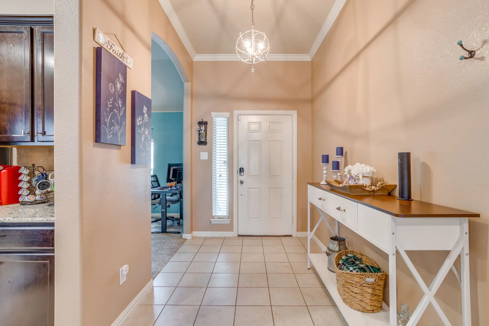Tiled entryway with crown molding, a decorative ceiling light fixture, and an arched doorway