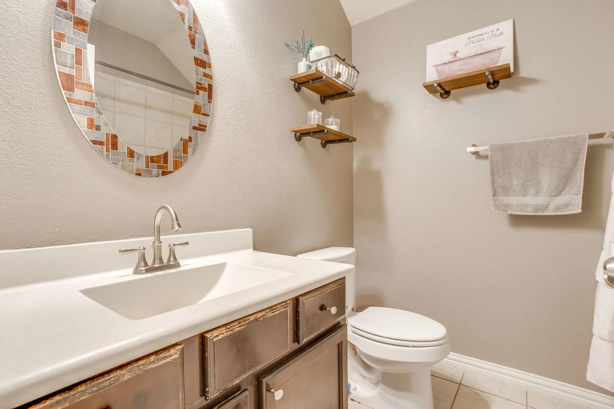 Vanity with an integrated sink, brushed nickel faucet, and mosaic-framed mirror