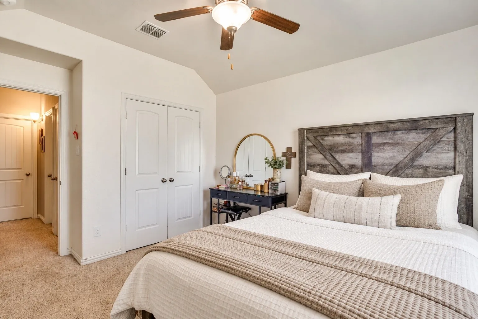 Vaulted ceiling, ceiling fan with light fixture, double-door closet, textured carpeting, and wood-finish headboard. Picture virtually edited