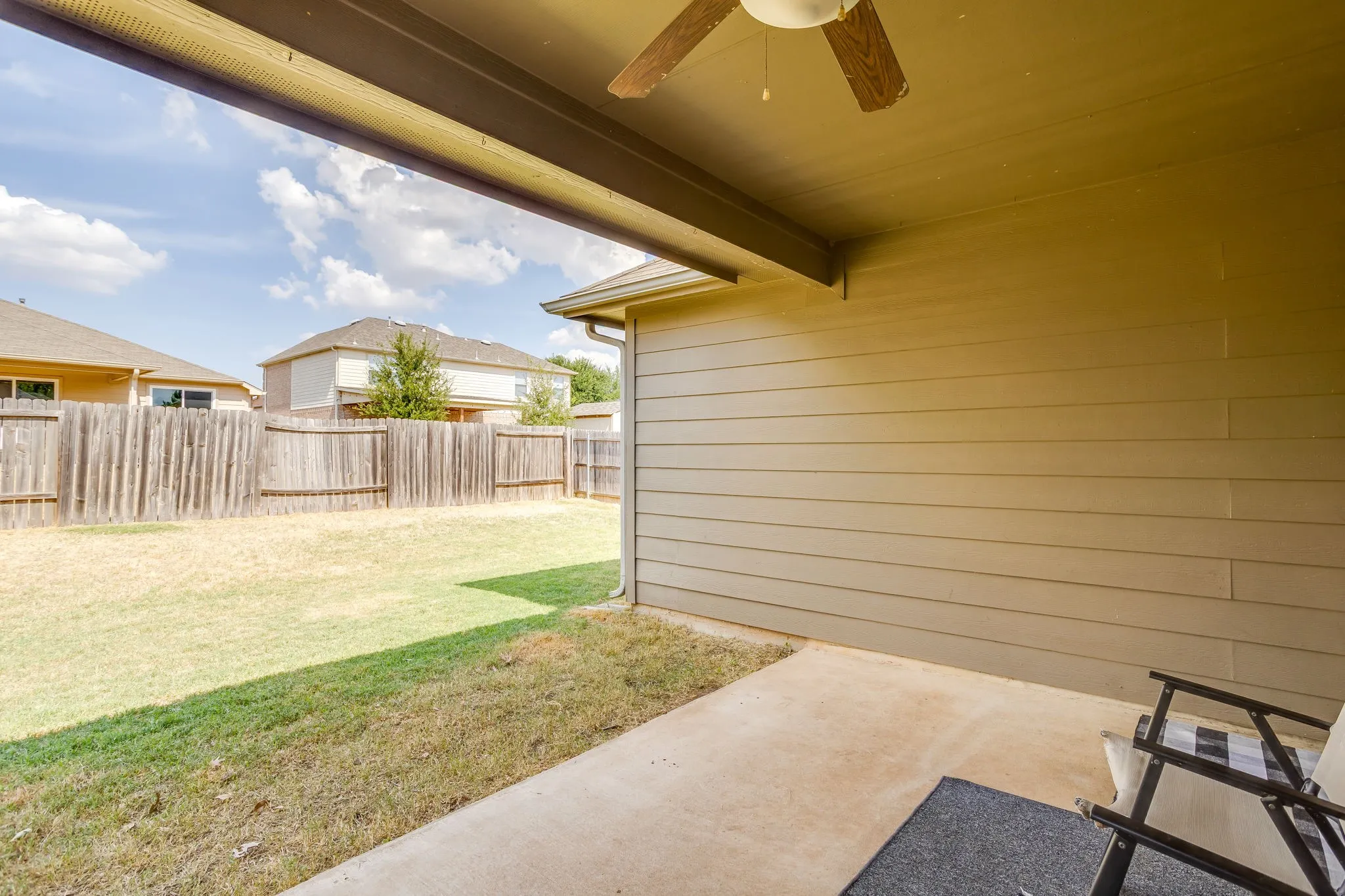 Covered patio with a ceiling fan, concrete flooring, and horizontal siding