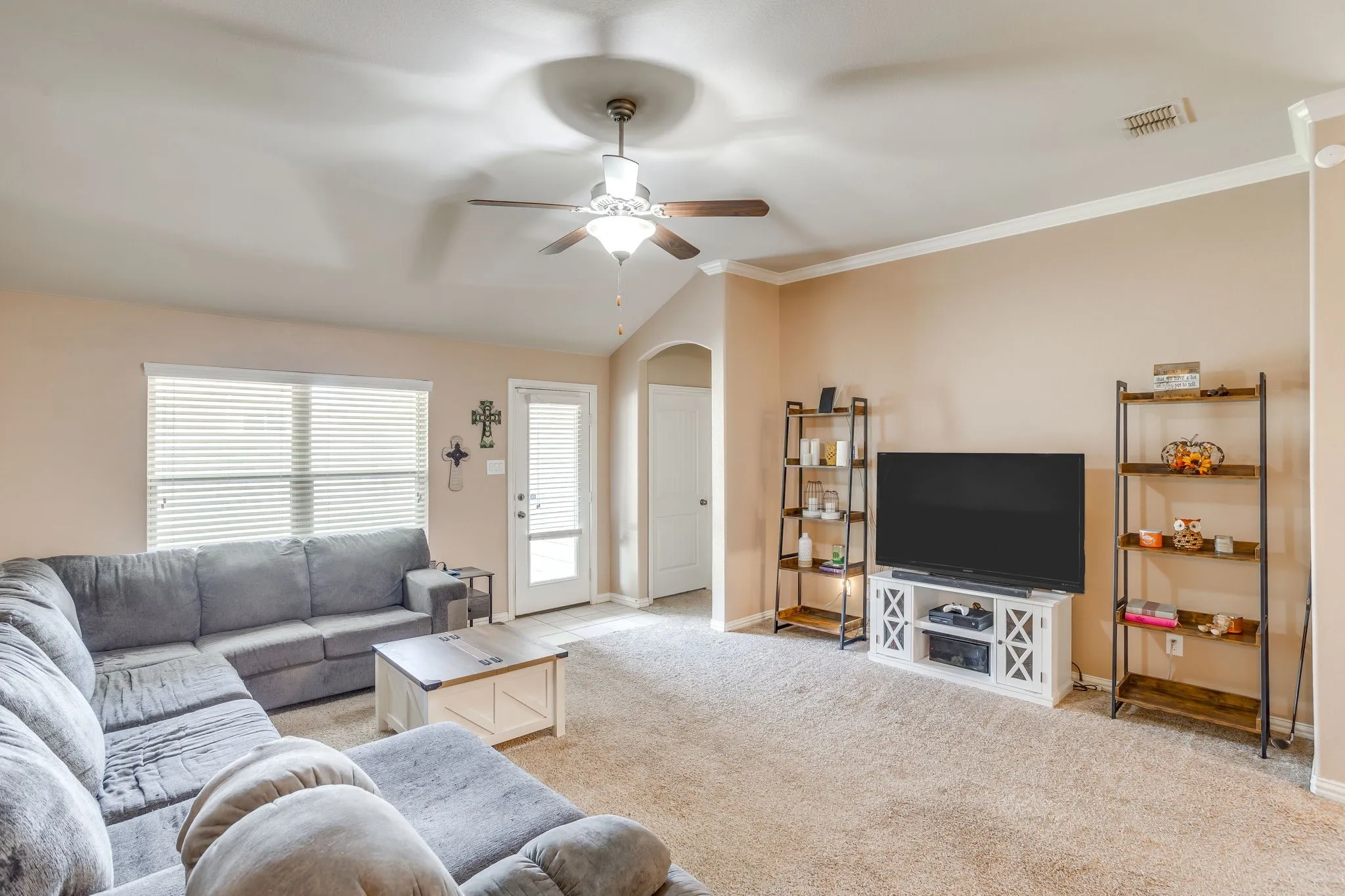 Vaulted ceiling with a ceiling fan, crown molding, and carpeted flooring
