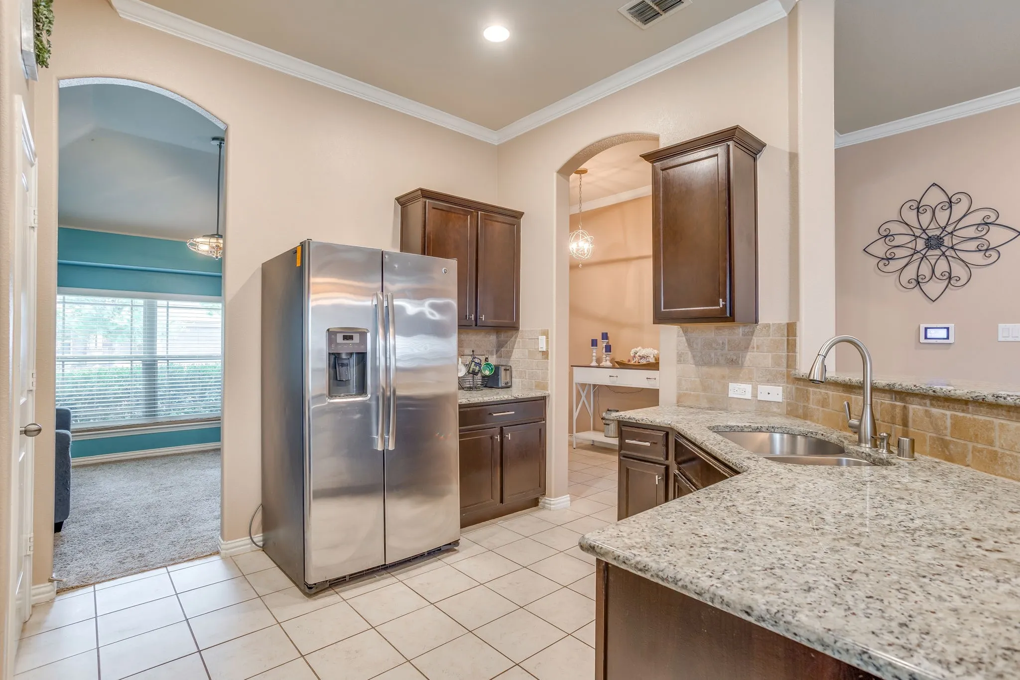 Kitchen featuring tile flooring, dark wood cabinetry, light granite countertops, and a tile backsplash