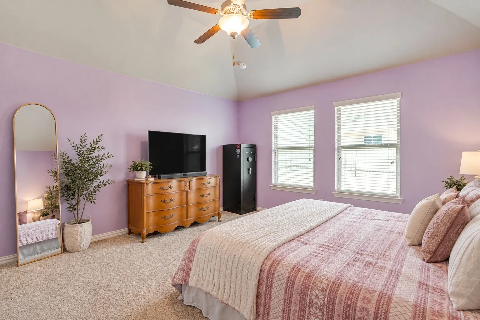 Tray ceiling with ceiling fan, two windows with blinds, and wall-to-wall carpeting. Picture virtually edited