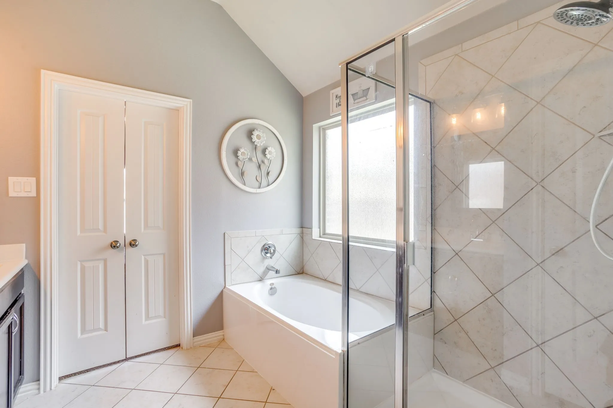 Enclosed shower with glass panel, white tiled flooring, built-in bathtub, and double panel doors