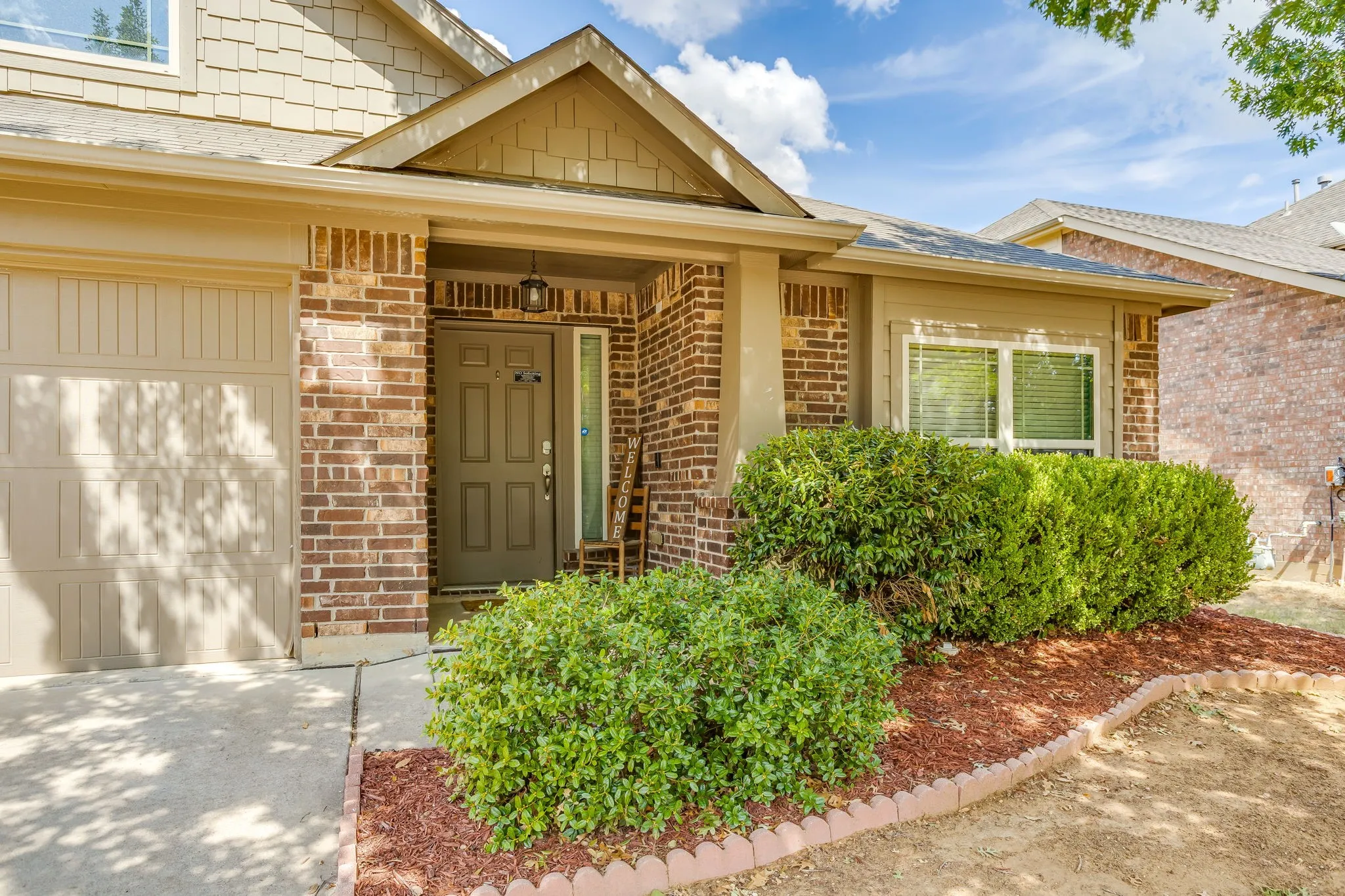 Brick and siding exterior with gabled roofline, covered entry, and integrated garage