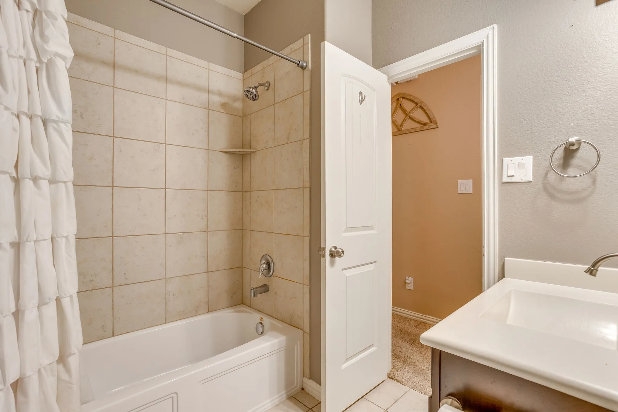 Bathtub with tile surround, shower fixture, and built-in shelf