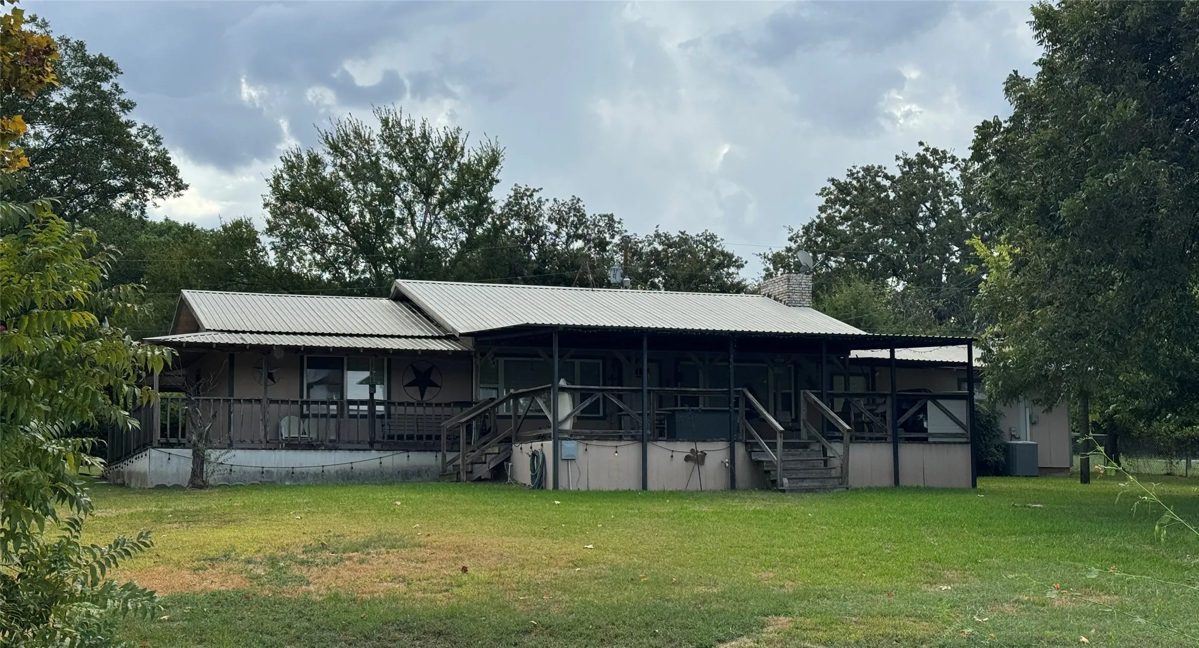 Corrugated metal roofing, expansive covered porch, wood exterior siding, and brick chimney