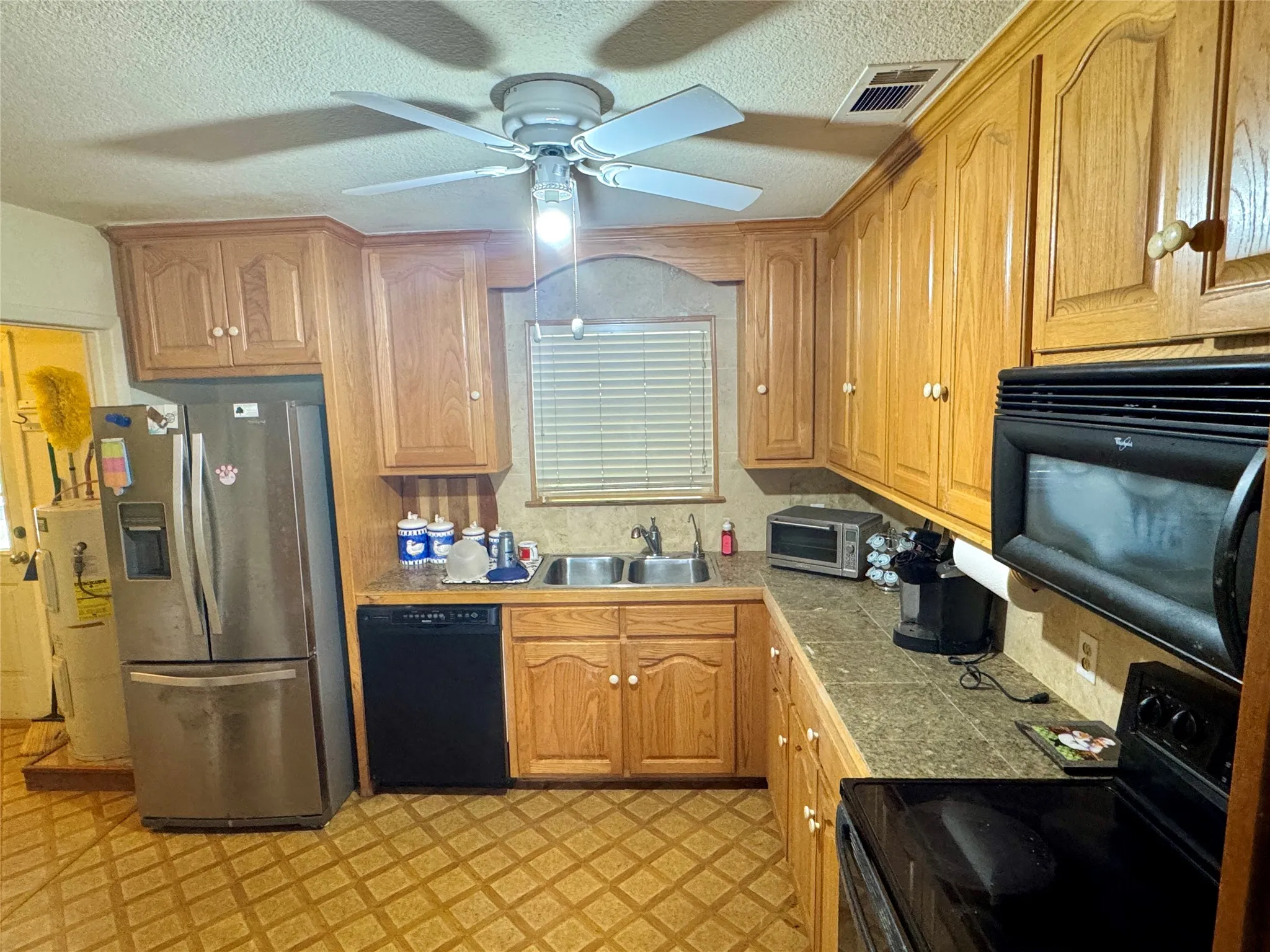Kitchen featuring wood cabinetry, laminate countertops, a double basin sink, and a ceiling fan