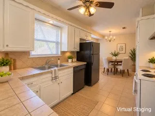 Kitchen featuring white cabinetry, tile countertops, tile flooring, and a ceiling fan