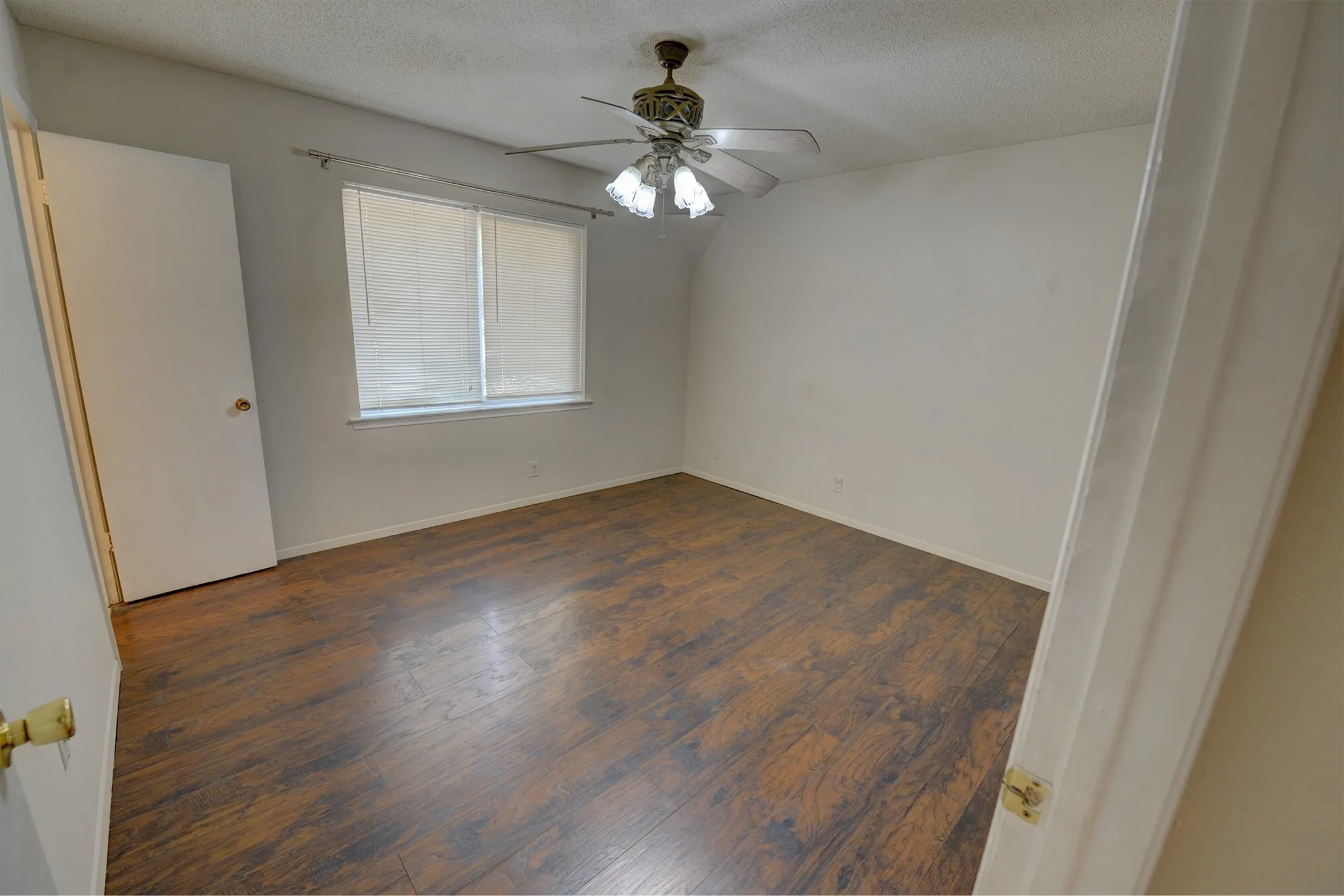 Wood-finish flooring, ceiling fan with light fixture, window with blinds, and neutral wall tones