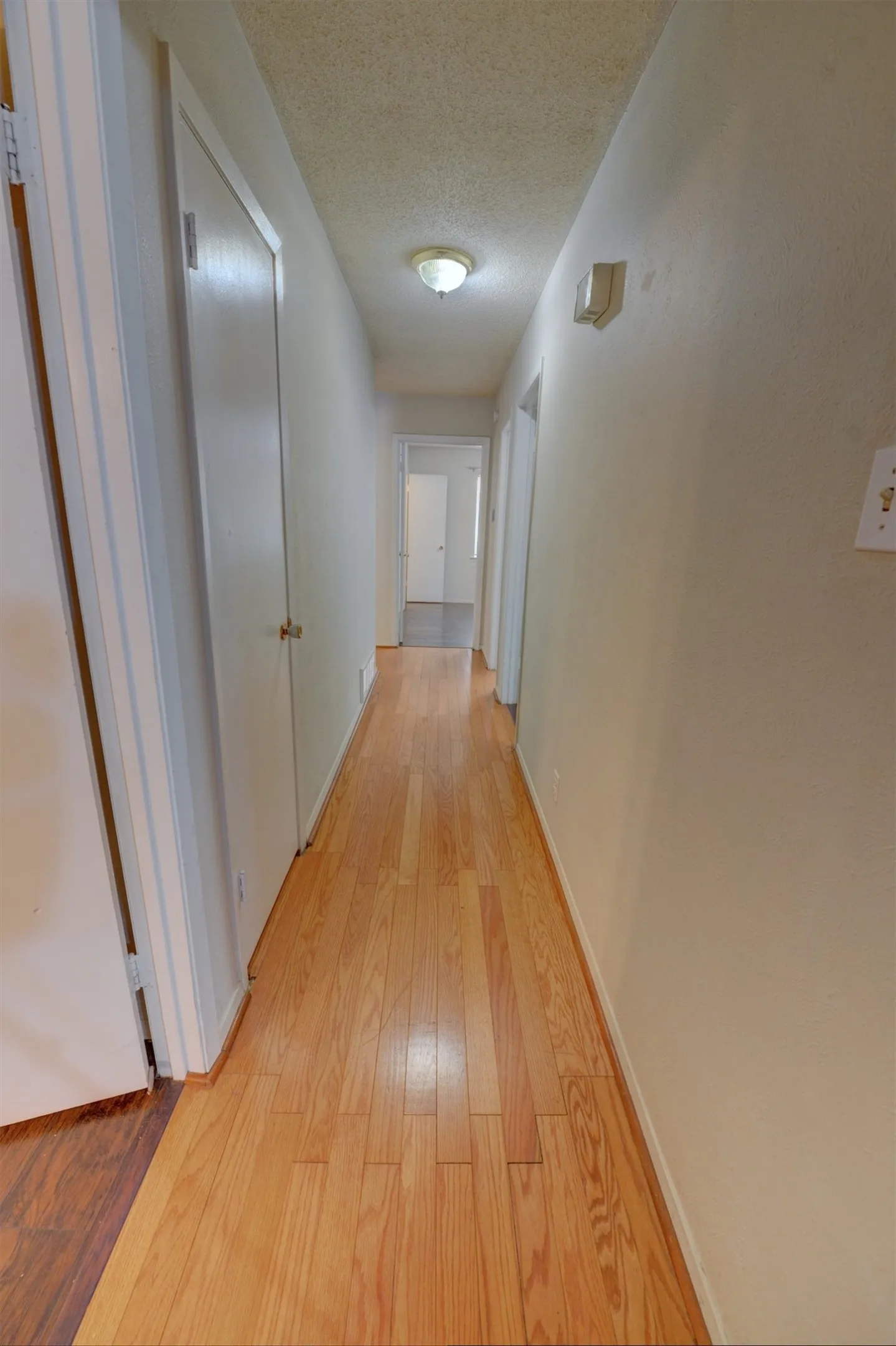 Hardwood flooring extending through a neutral-toned hallway