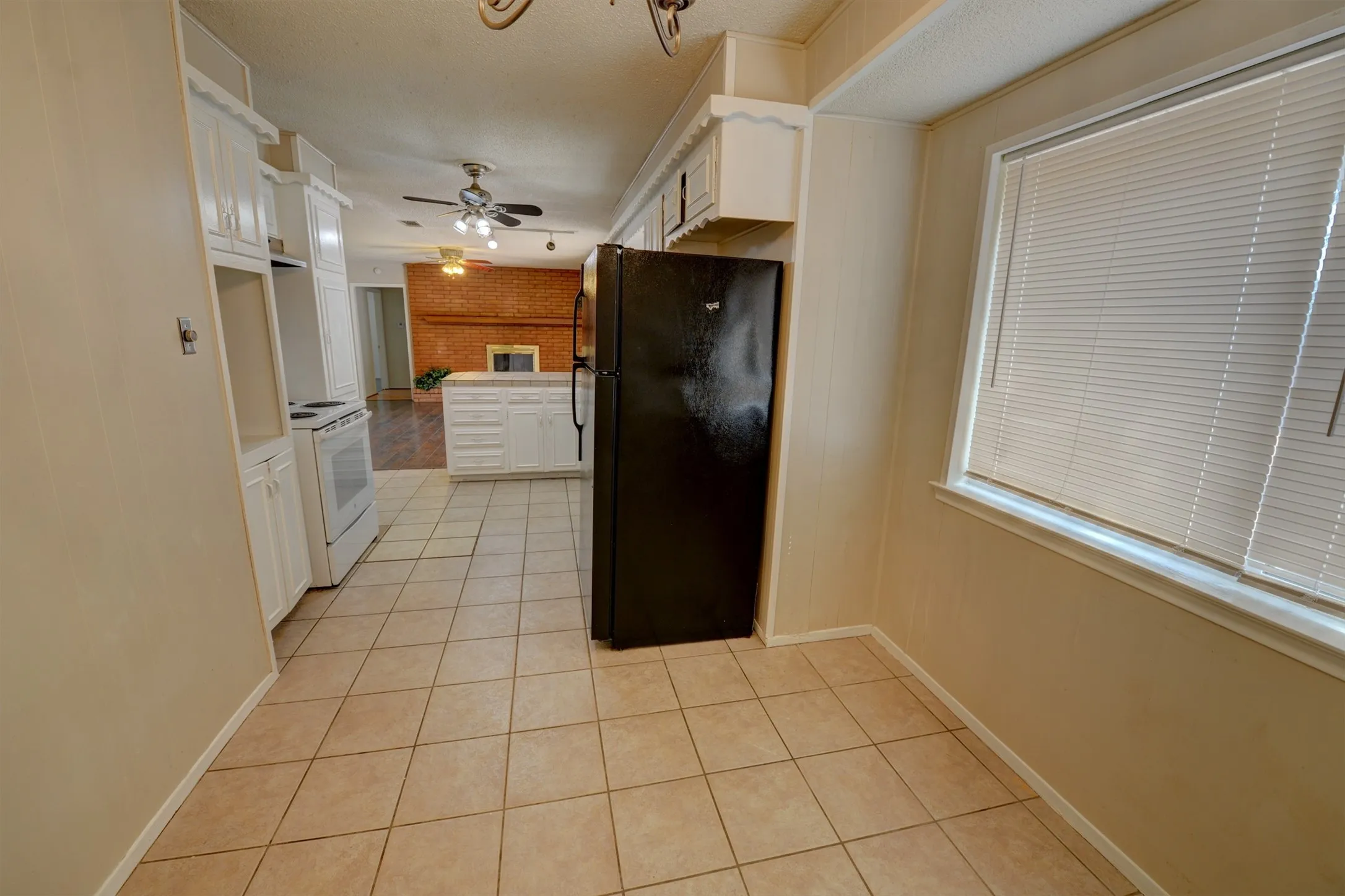 Kitchen featuring ceramic tile flooring, white cabinetry, white appliances, and a window with blinds