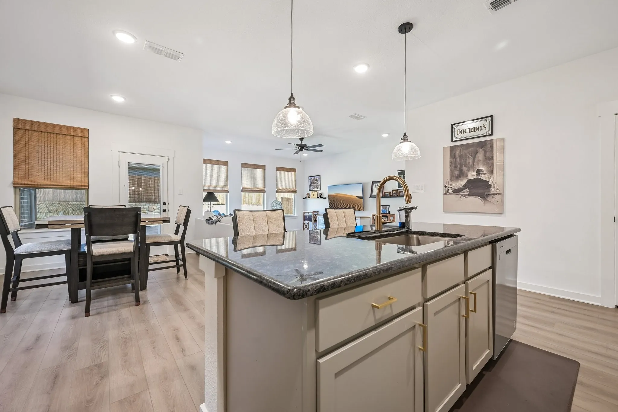Kitchen island with dark countertop, undermount sink, and brass-tone faucet