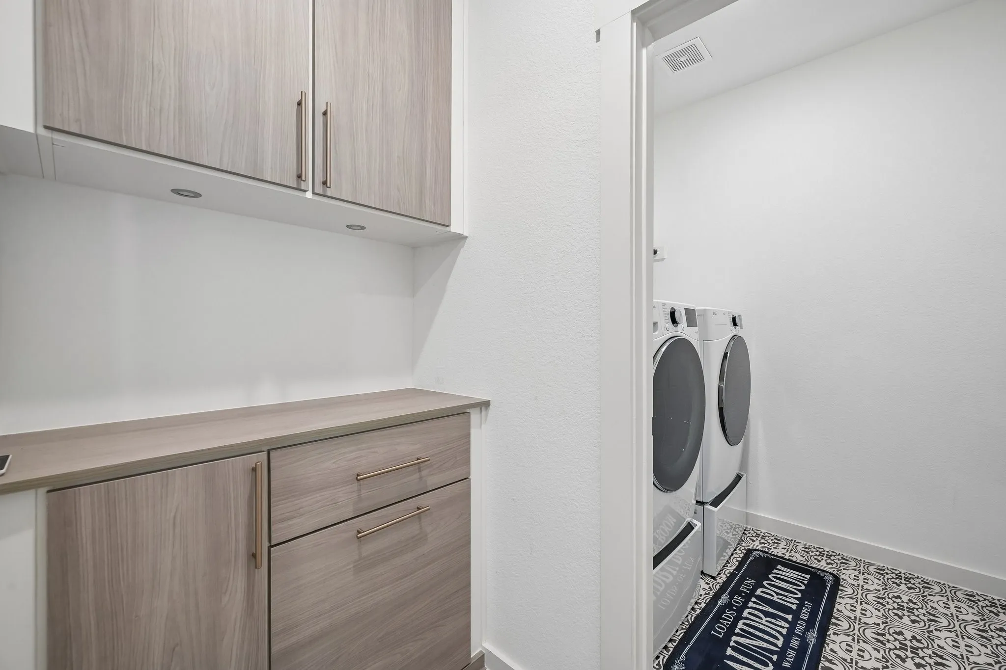 Laundry area with light wood-finish cabinetry, integrated countertop, and recessed lighting