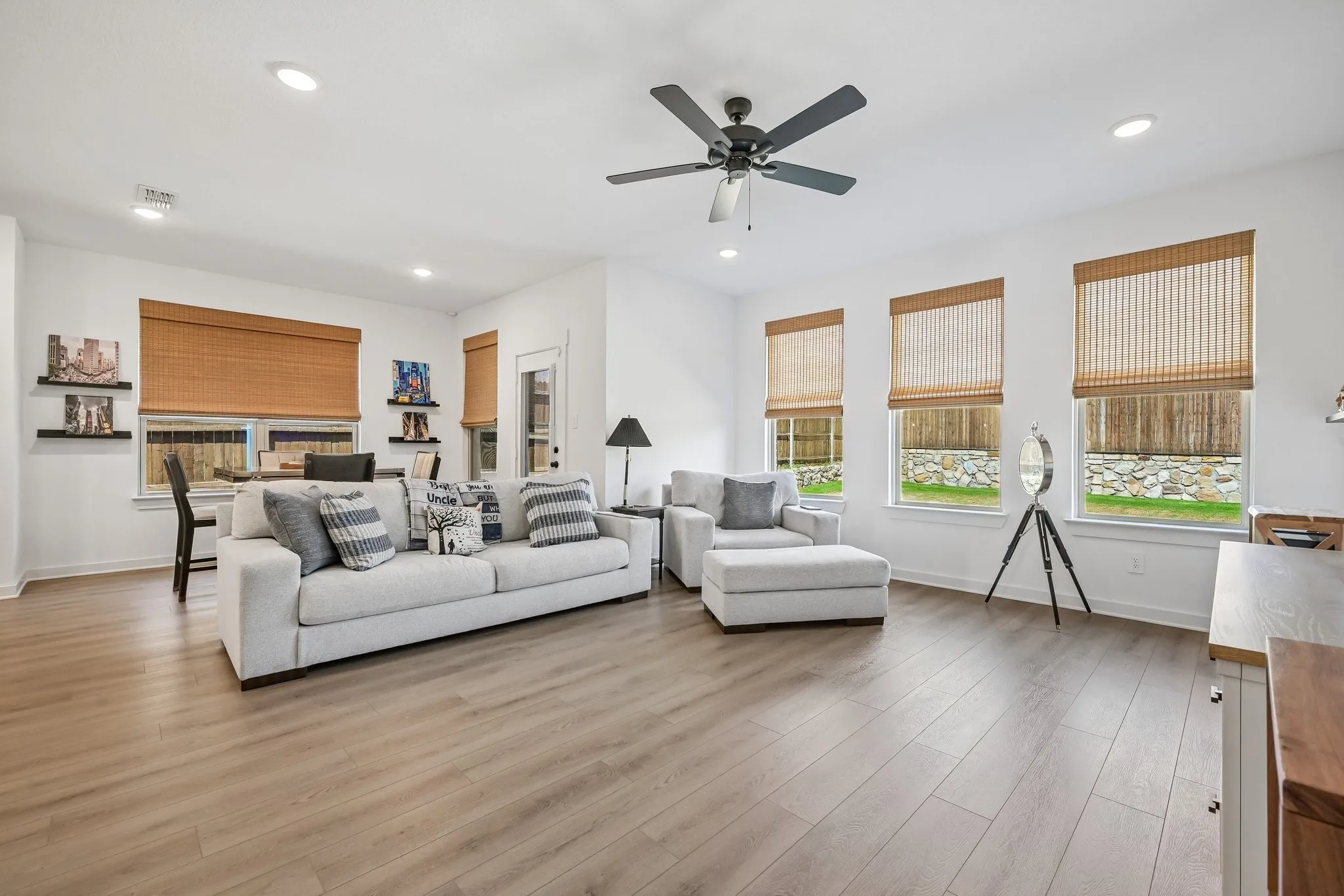 Recessed lighting throughout, wood-finish flooring, ceiling fan, and multiple windows with woven shades