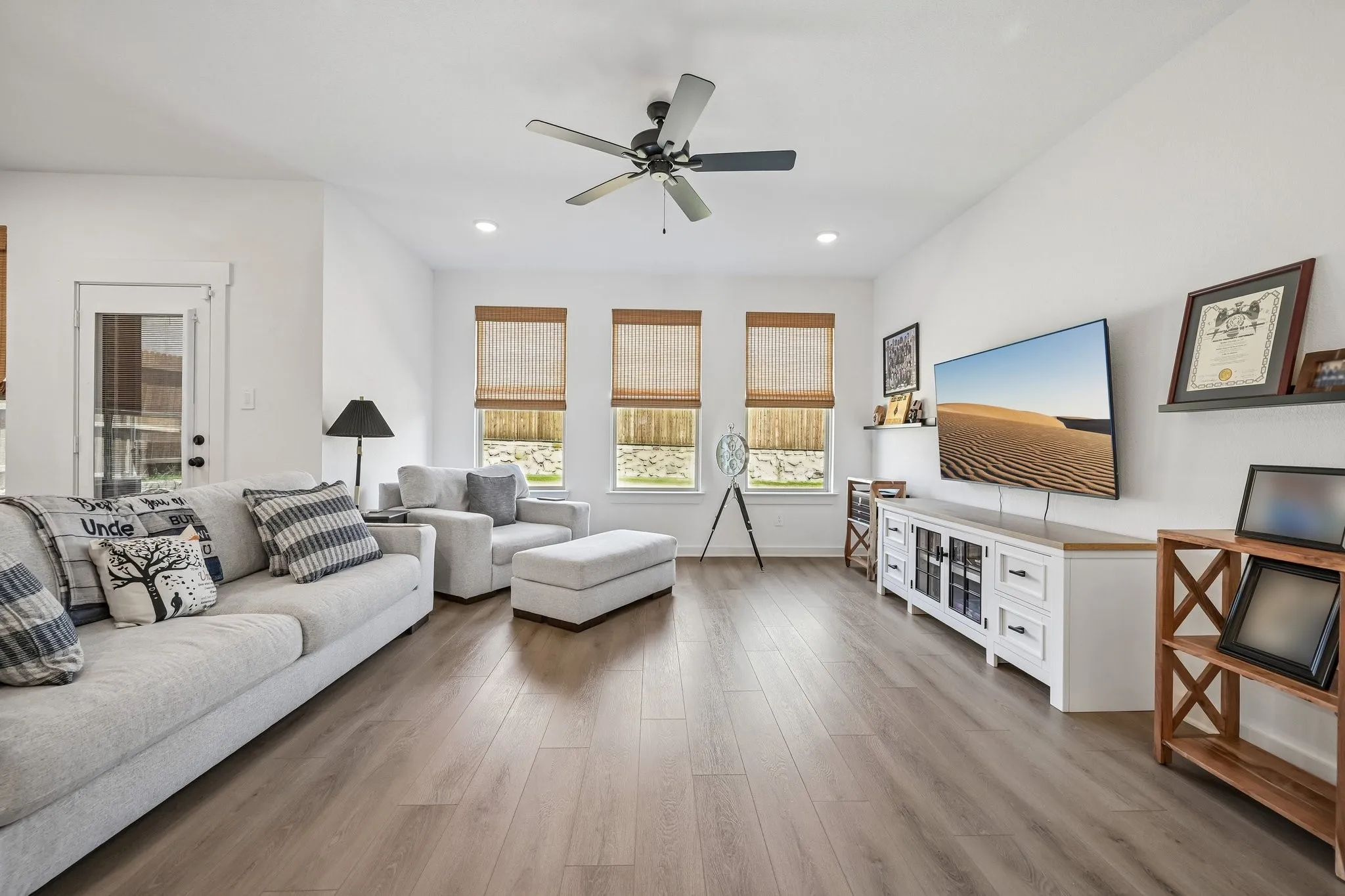 Recessed lighting, wood-finish flooring, ceiling fan, and multiple windows with woven shades