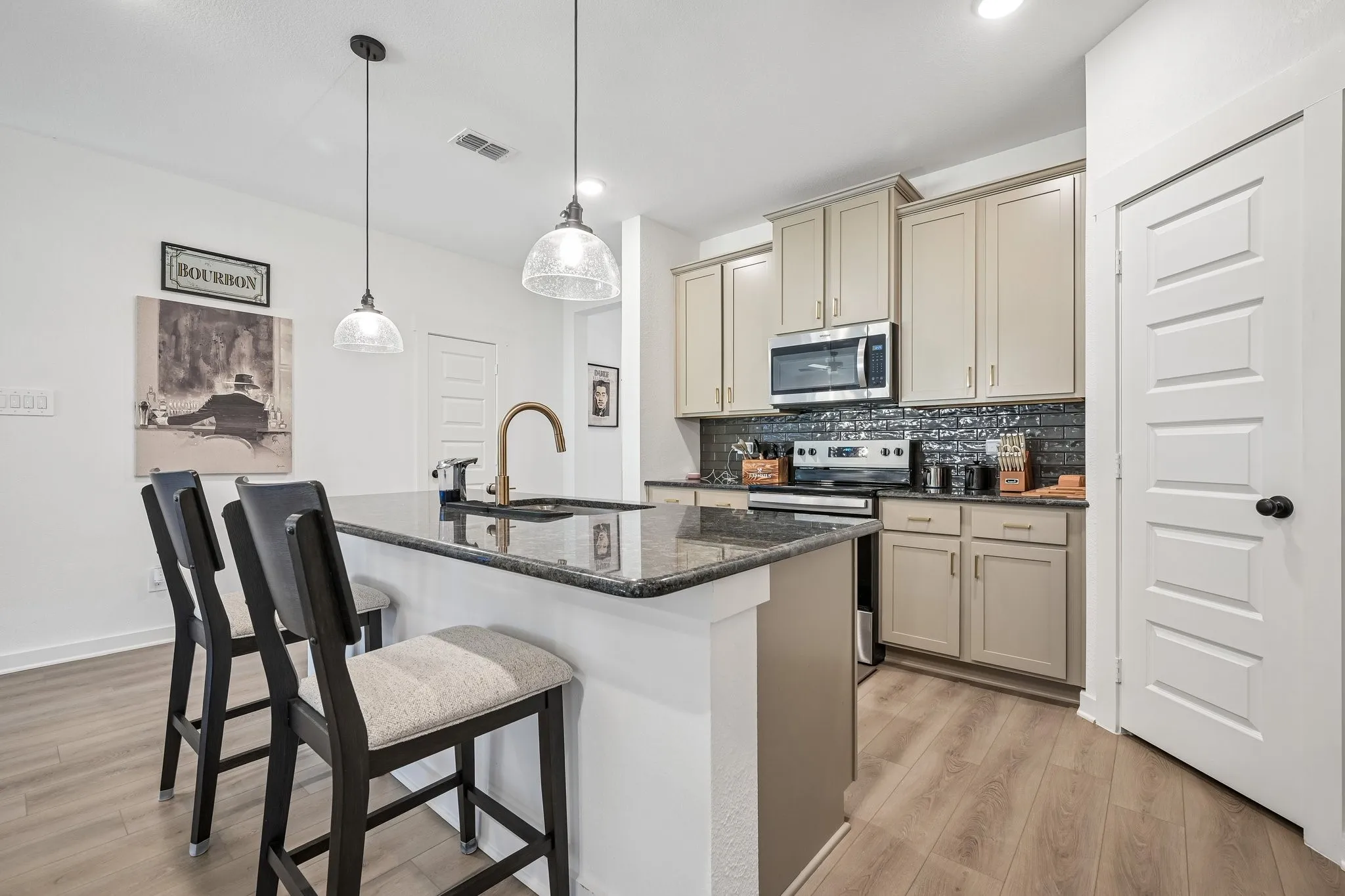 Kitchen island with a dark countertop and bronze-finish faucet