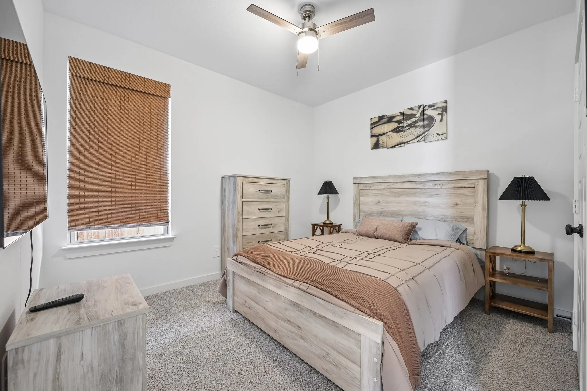 Carpeted room featuring a ceiling fan, a window with a woven shade, and white walls