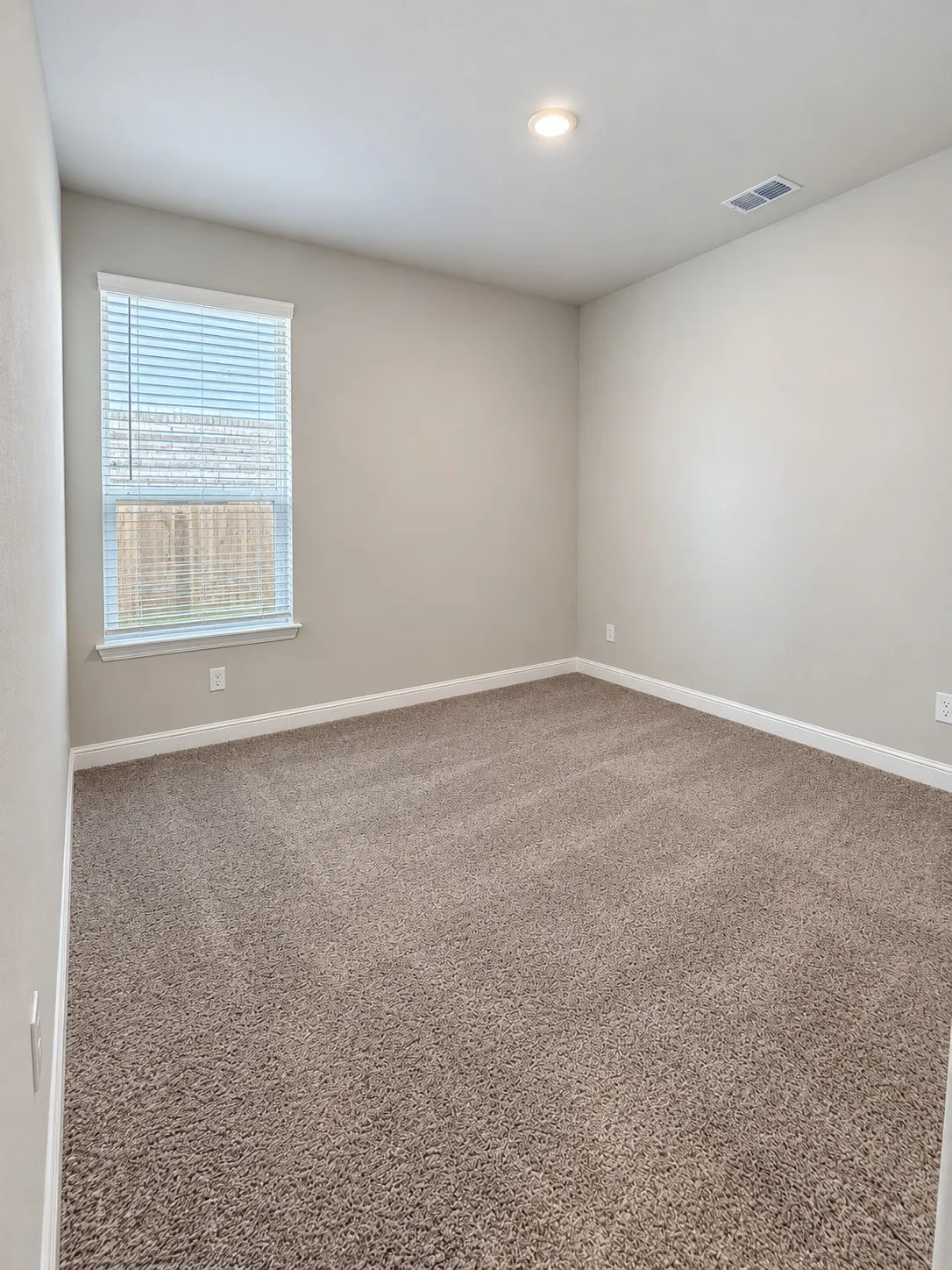 Recessed ceiling lighting, neutral wall paint, carpeted flooring, and a single window with blinds