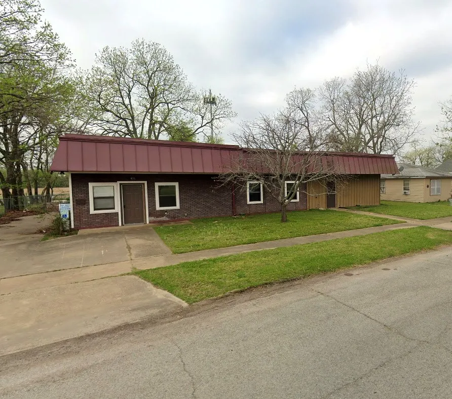 Brick exterior with a red metal roof and a concrete driveway