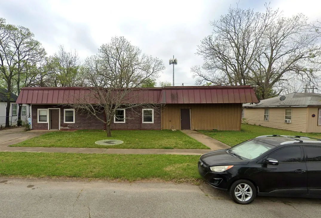 Red metal roof, brick and wood-paneled exterior, dual entryways, concrete walkway, and manicured lawn