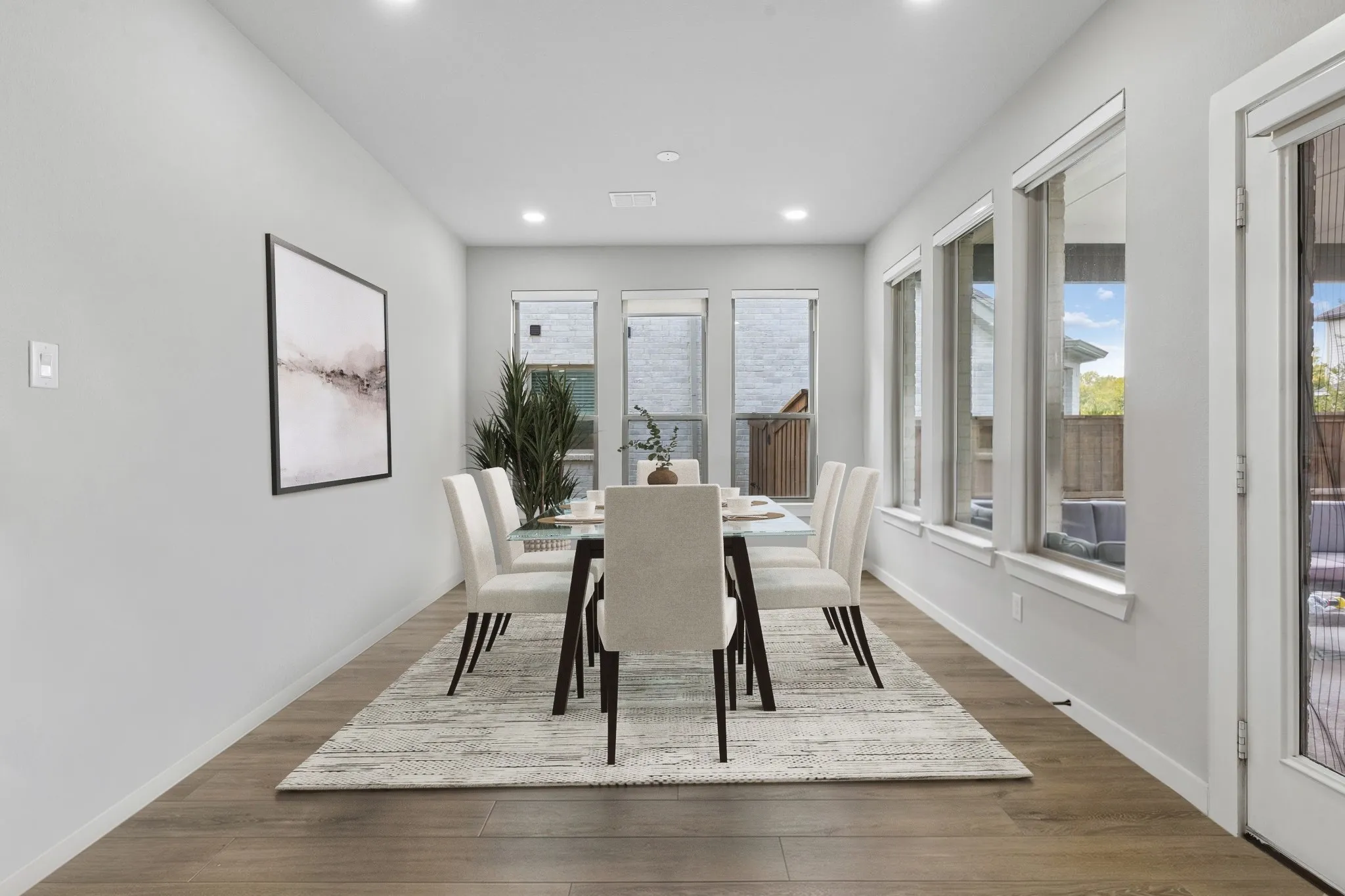 Recessed lighting, wood-finish flooring, multiple windows, and a glass-paneled door