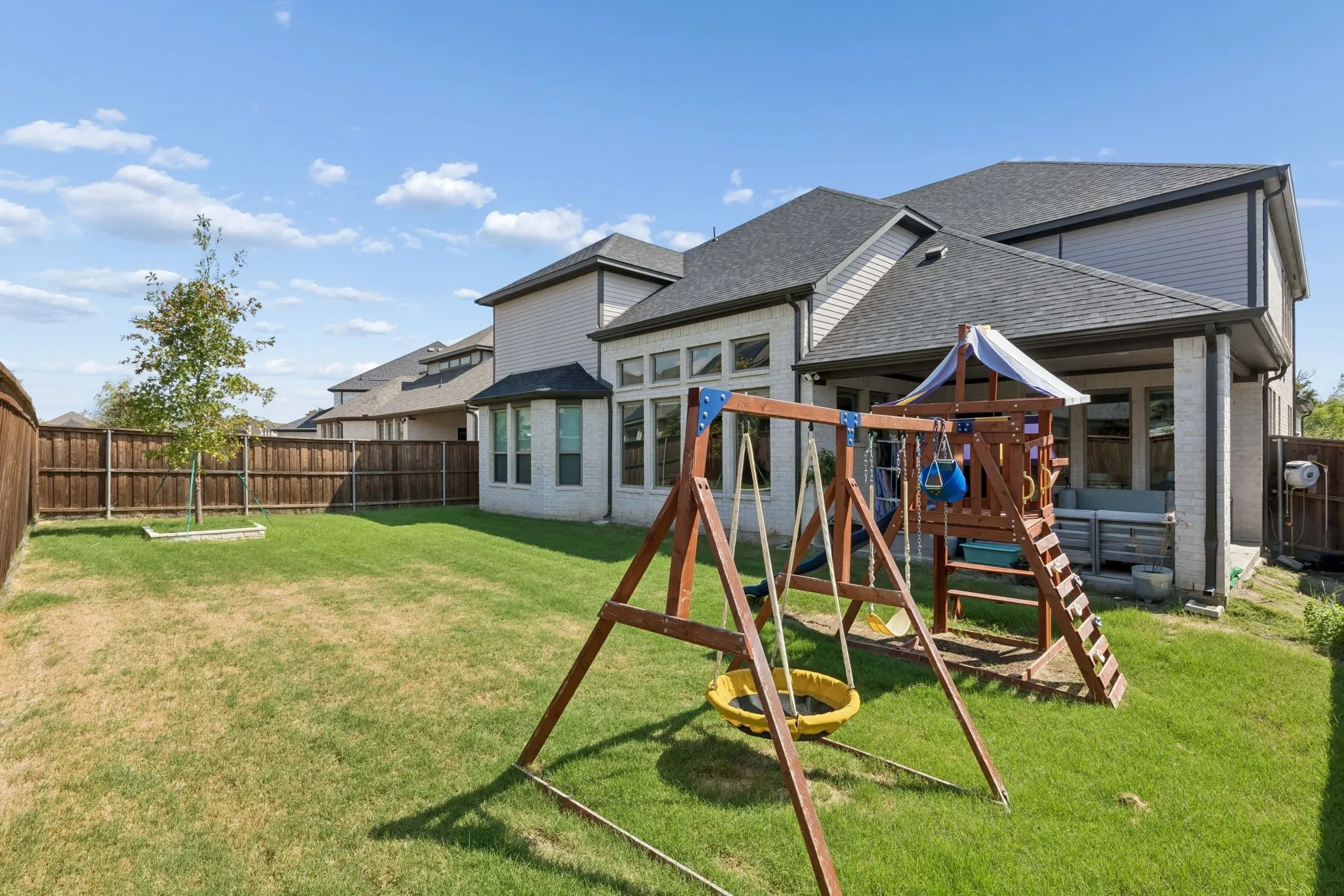 Expansive backyard featuring a privacy fence, covered patio, and brick exterior