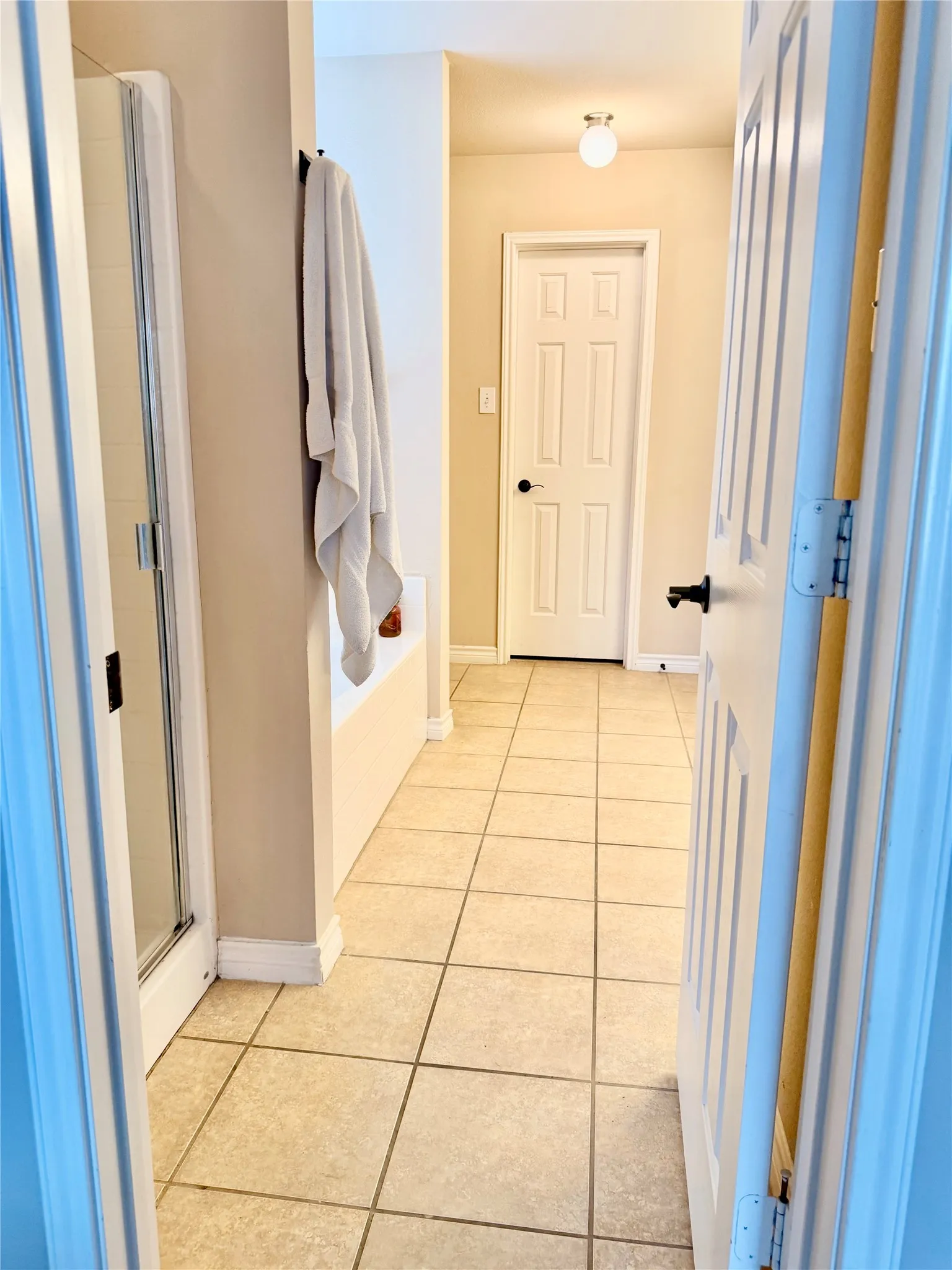 Tile flooring extending through the space, built-in bathtub, and a glass-enclosed shower