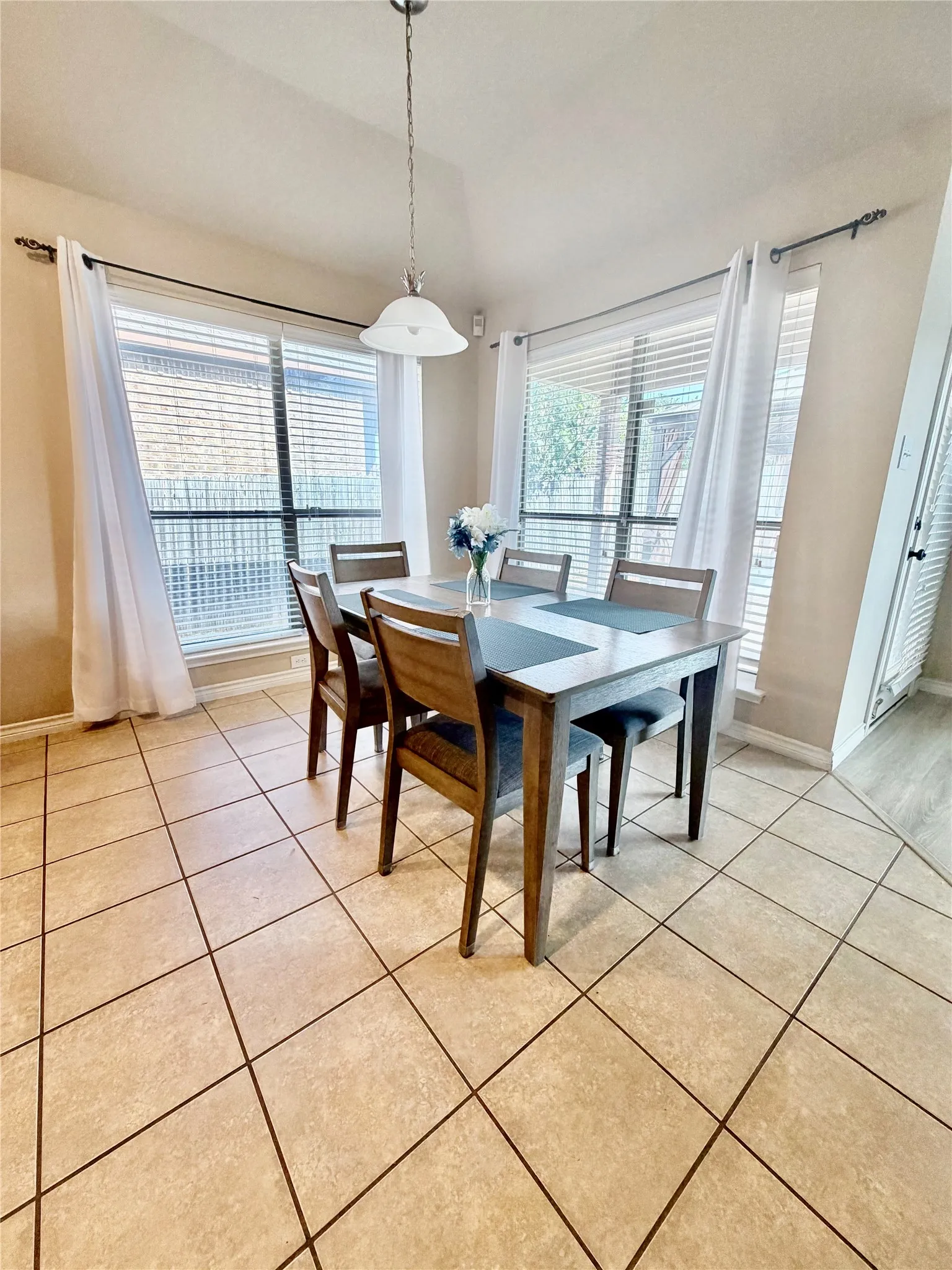 Tile flooring, vaulted ceiling, pendant light fixture, multiple windows, window blinds