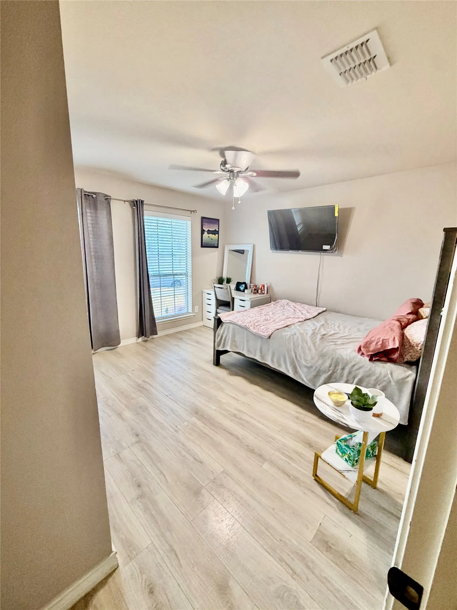 Spacious room featuring wood-finish flooring, a ceiling fan, and a window with blinds