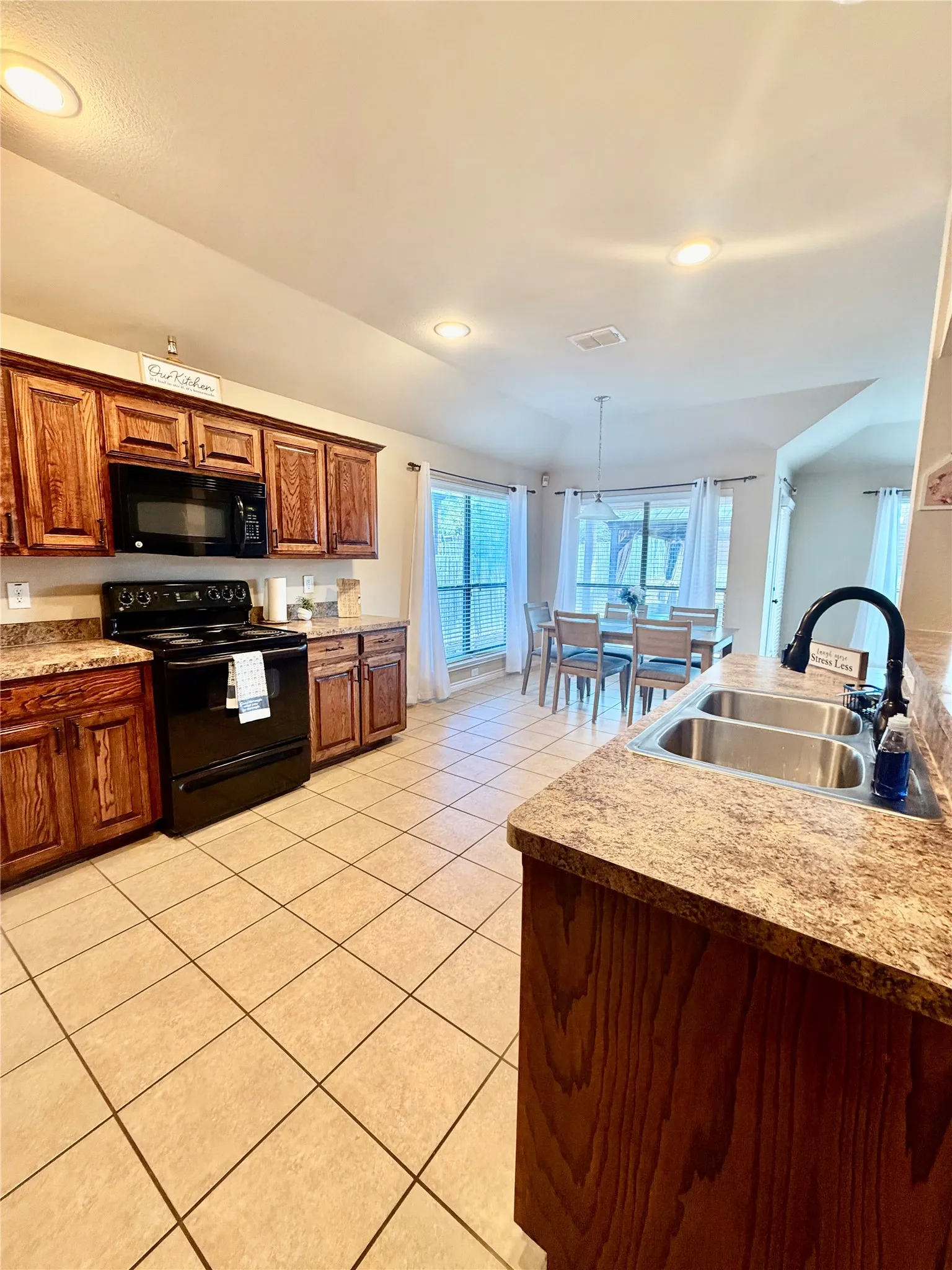 Kitchen featuring wood cabinetry, stone-finish countertops, and stainless steel double sink