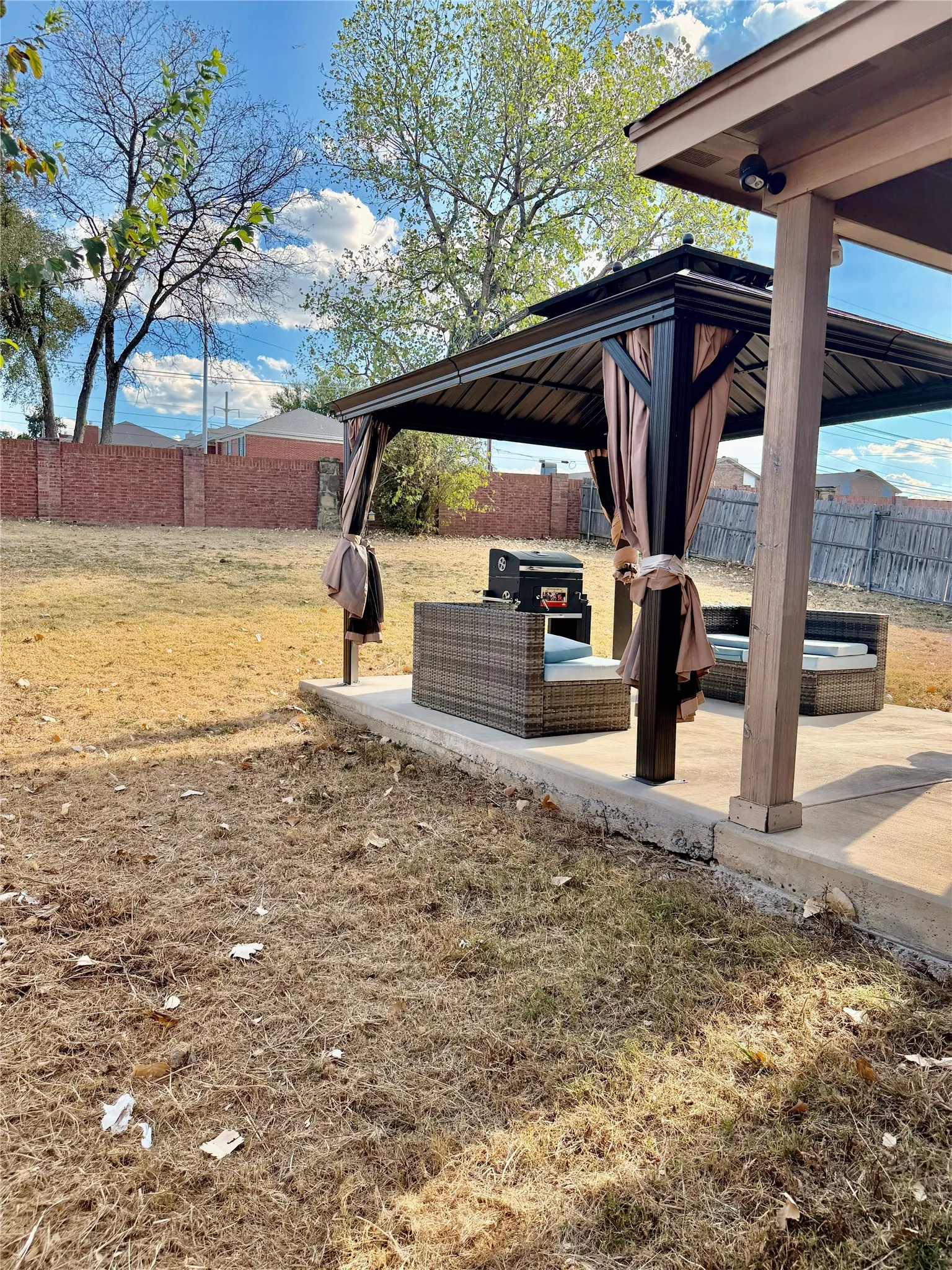 Concrete patio area featuring a built-in gazebo with a metal frame and privacy drapes