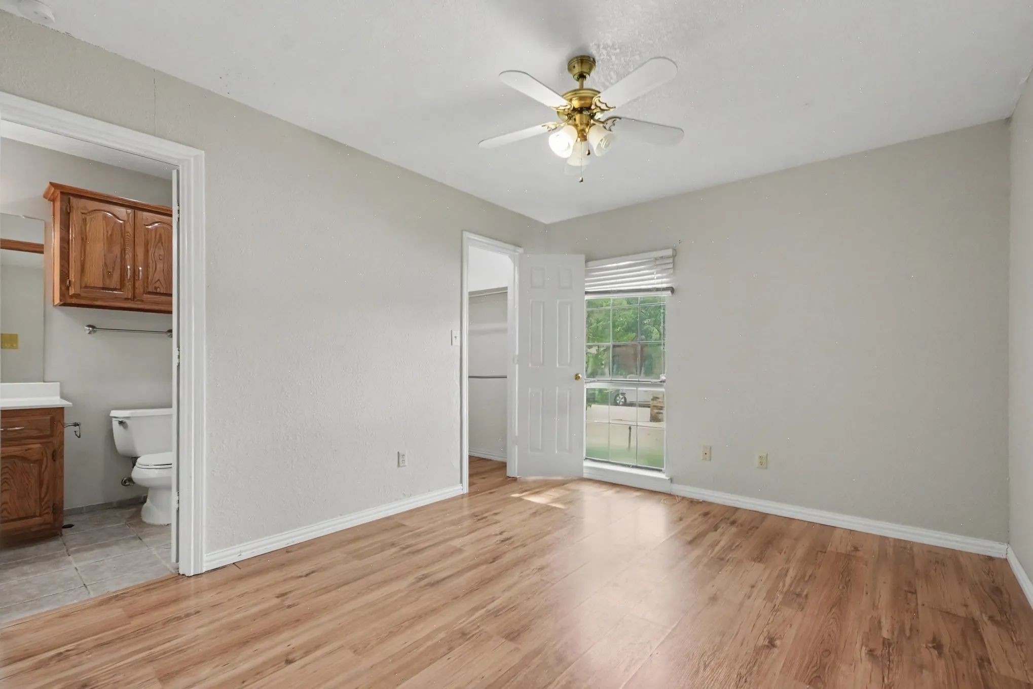 Wood-finish flooring, ceiling fan with integrated lighting, and a white window blind