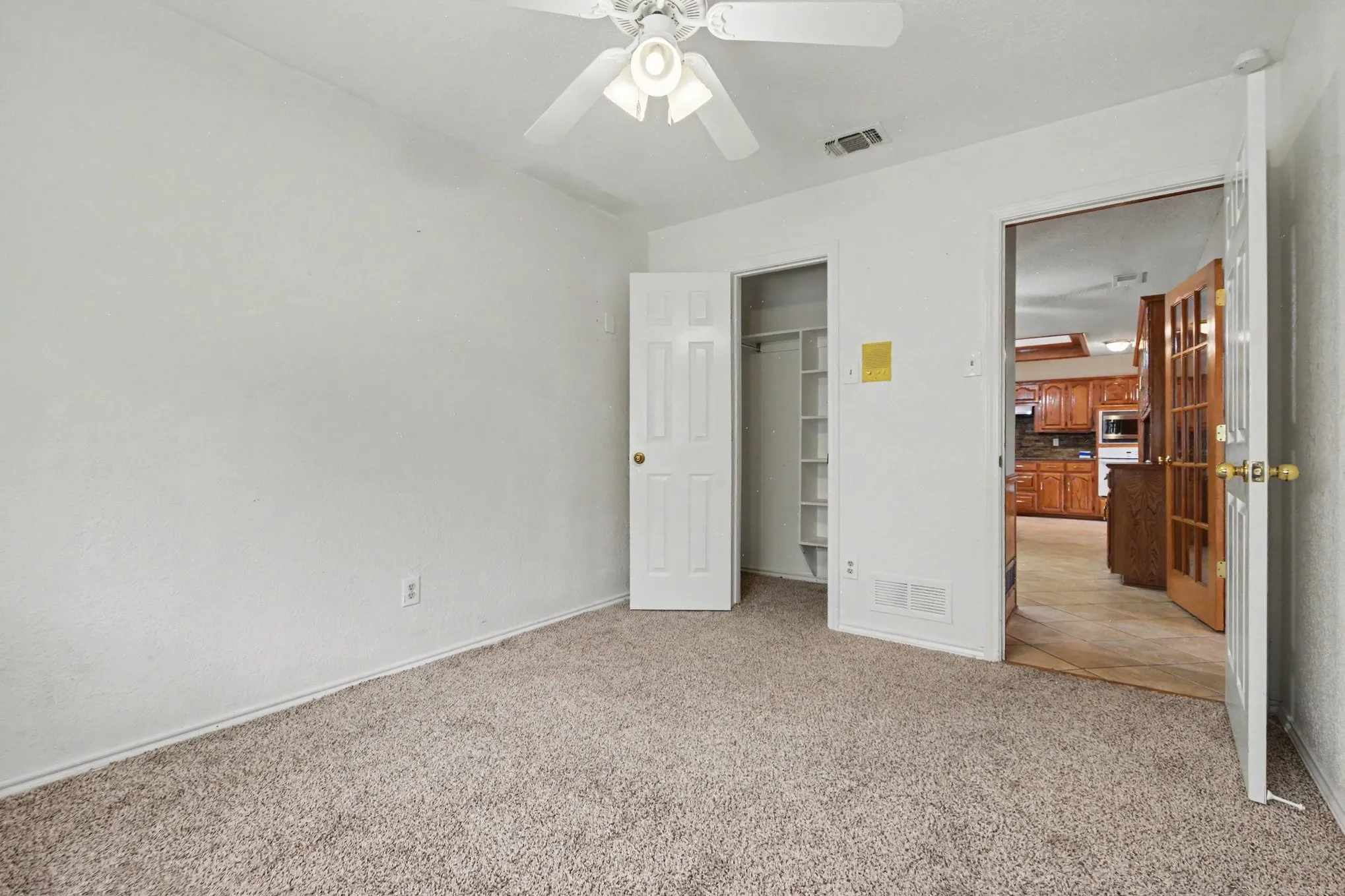 Neutral-toned carpeting, white walls, and a ceiling fan with integrated lighting