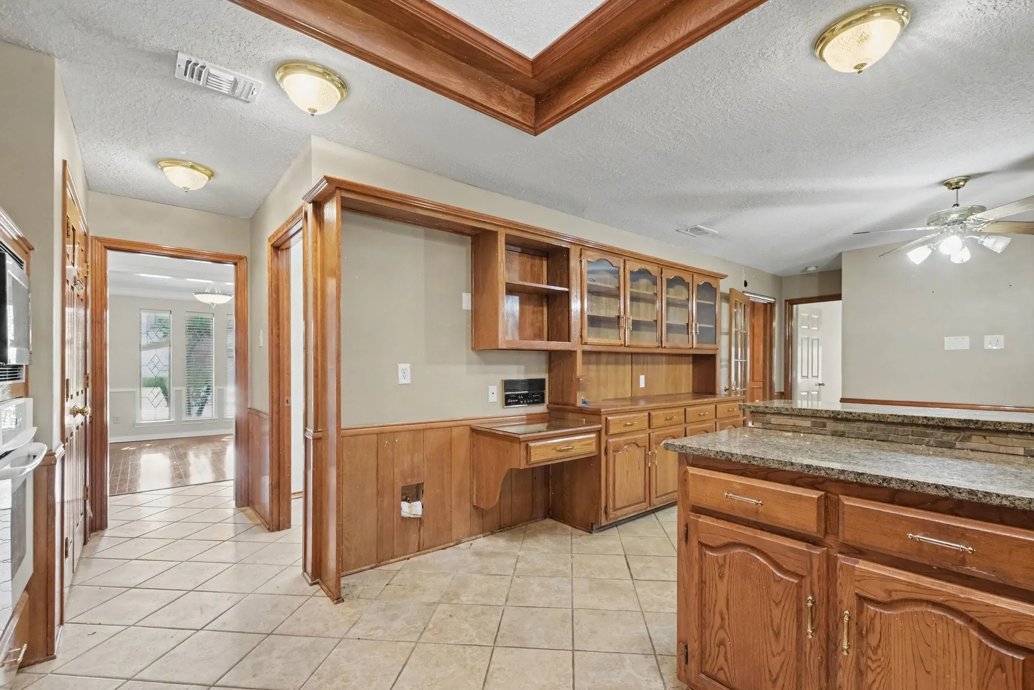 Kitchen featuring wood-finish cabinetry, built-in desk, tile flooring, and a granite-style countertop