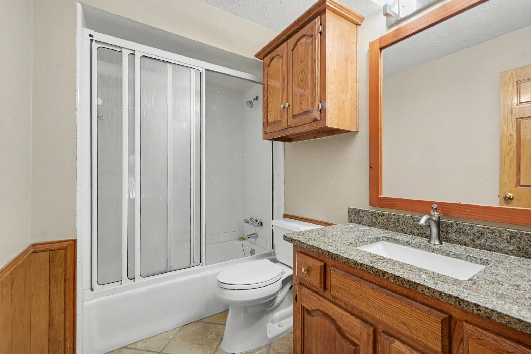 Bathroom featuring a built-in vanity with a granite-style countertop, undermount sink, and wood-finish cabinetry
