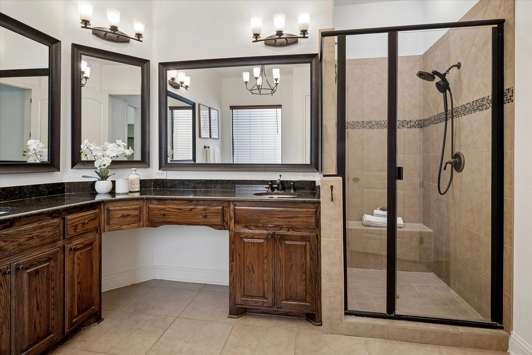 Primary bathroom featuring a shower with a built in bench, vanity seating, dual sinks, and a separate tub.