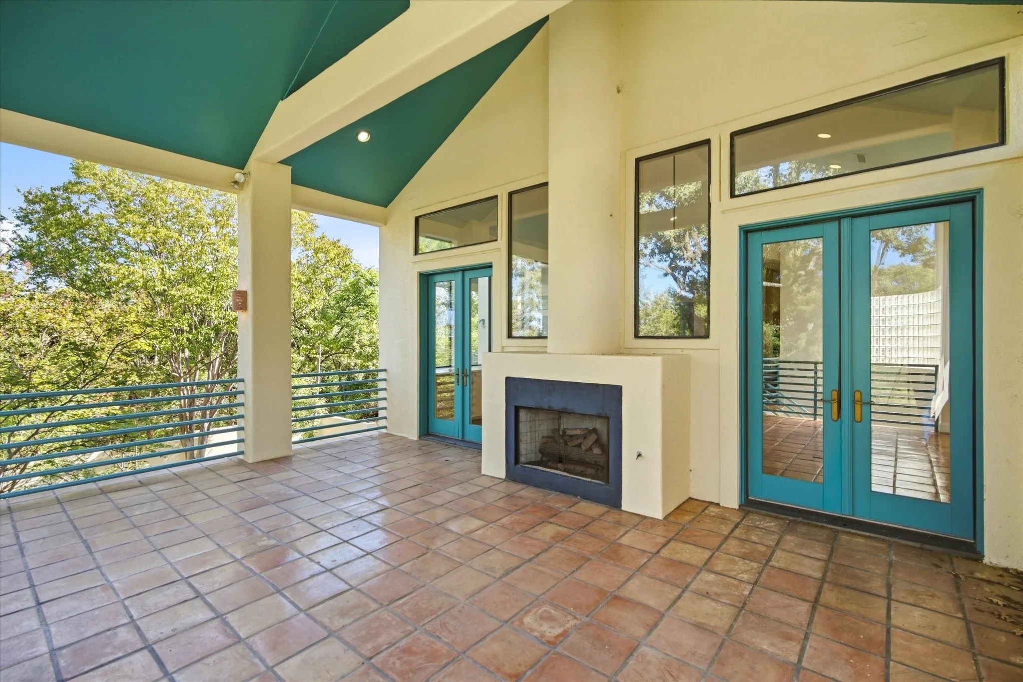 Covered patio featuring terracotta tile flooring, a built-in fireplace, and expansive glass doors