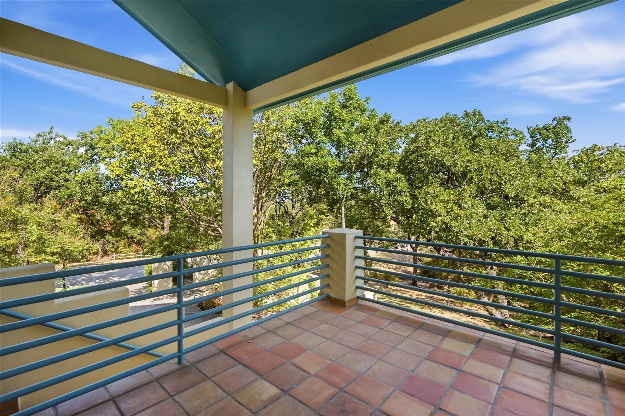 Covered balcony with terracotta tile flooring, painted metal railings, and a painted ceiling