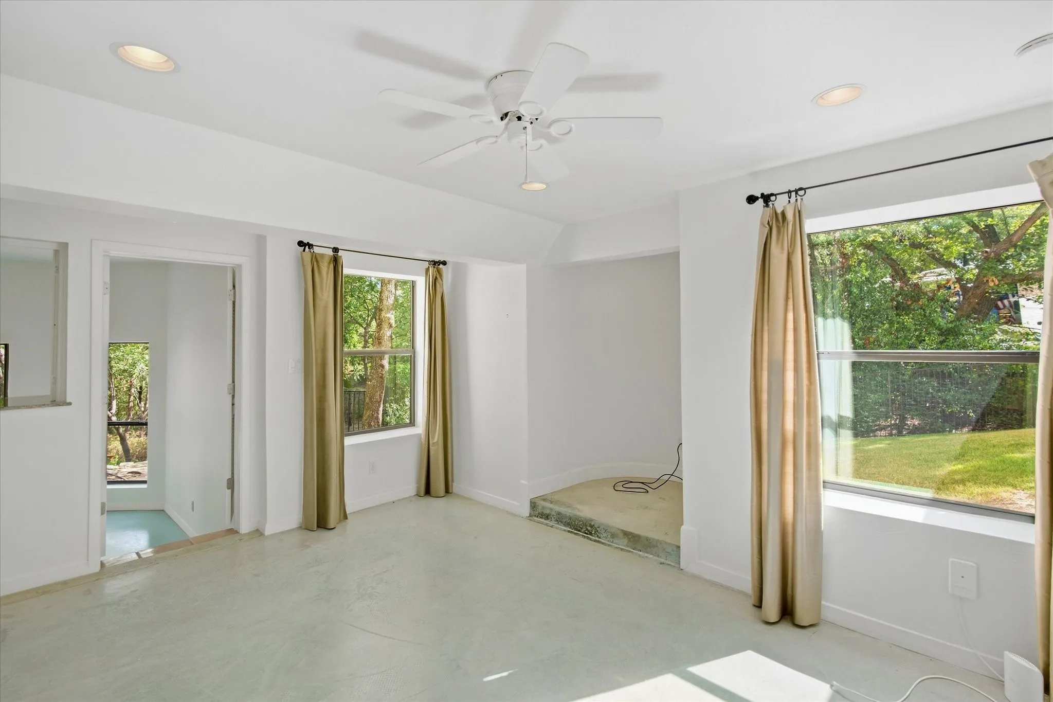 Recessed lighting, ceiling fan, multiple windows, and a raised platform area