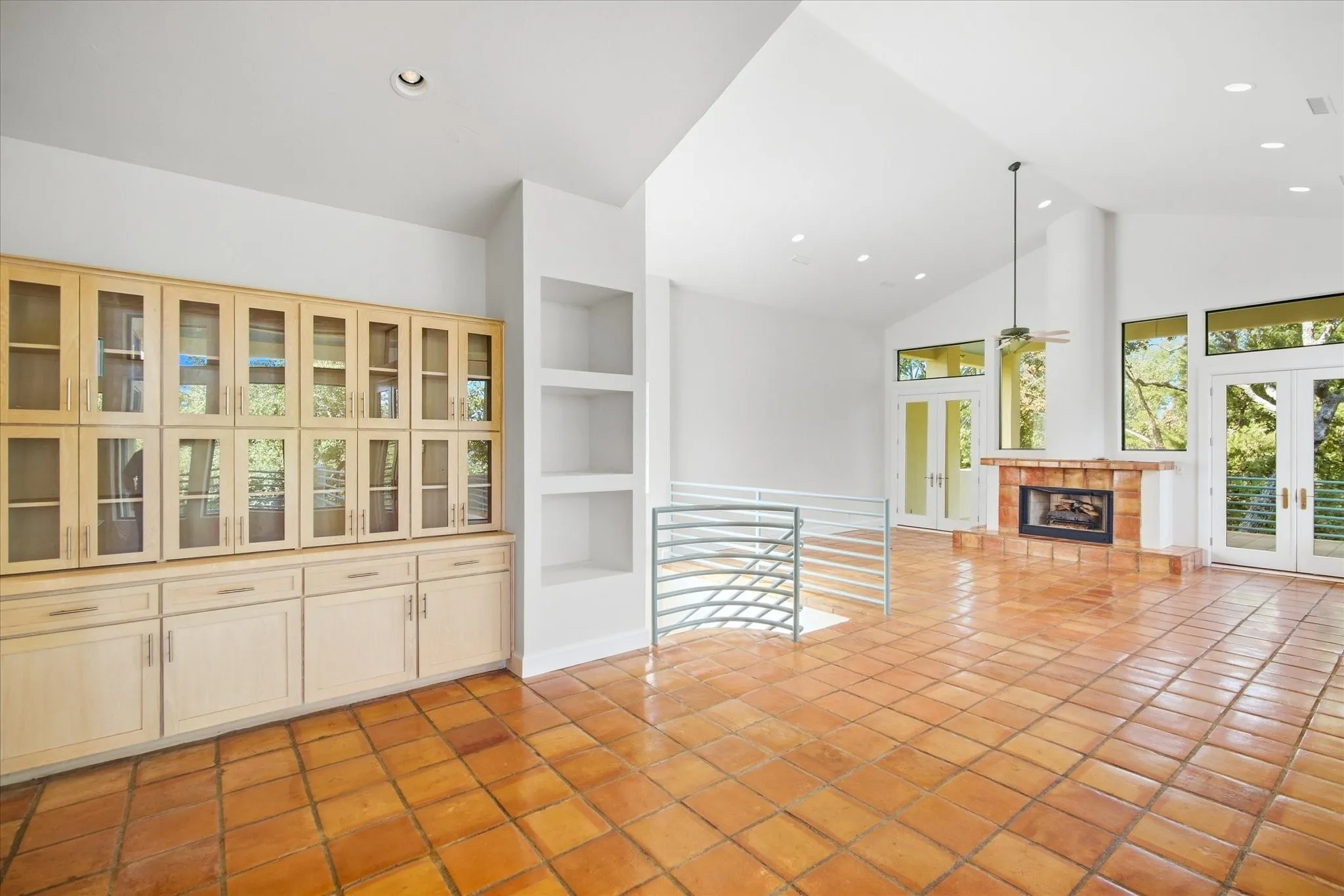 Vaulted ceilings, built-in cabinetry with glass fronts, recessed lighting, tile flooring, and a fireplace with a tile surround